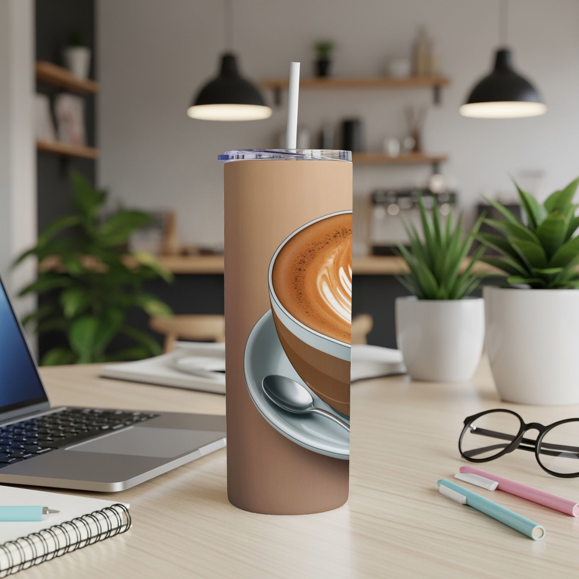 Brown tumbler with latte art and straw on desk.