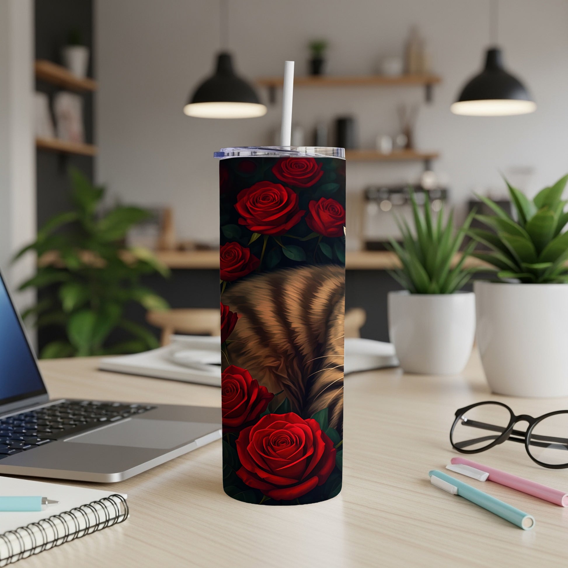 Cat sleeping amongst red roses on a tumbler with a straw.