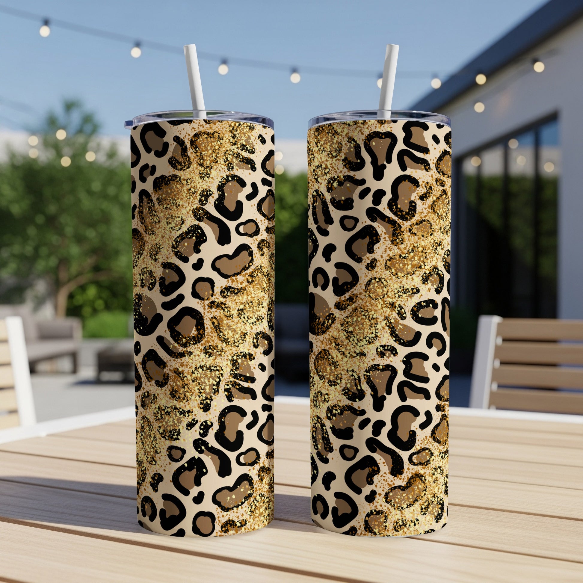 Two tumblers with leopard print and gold glitter patterns on a wooden table.