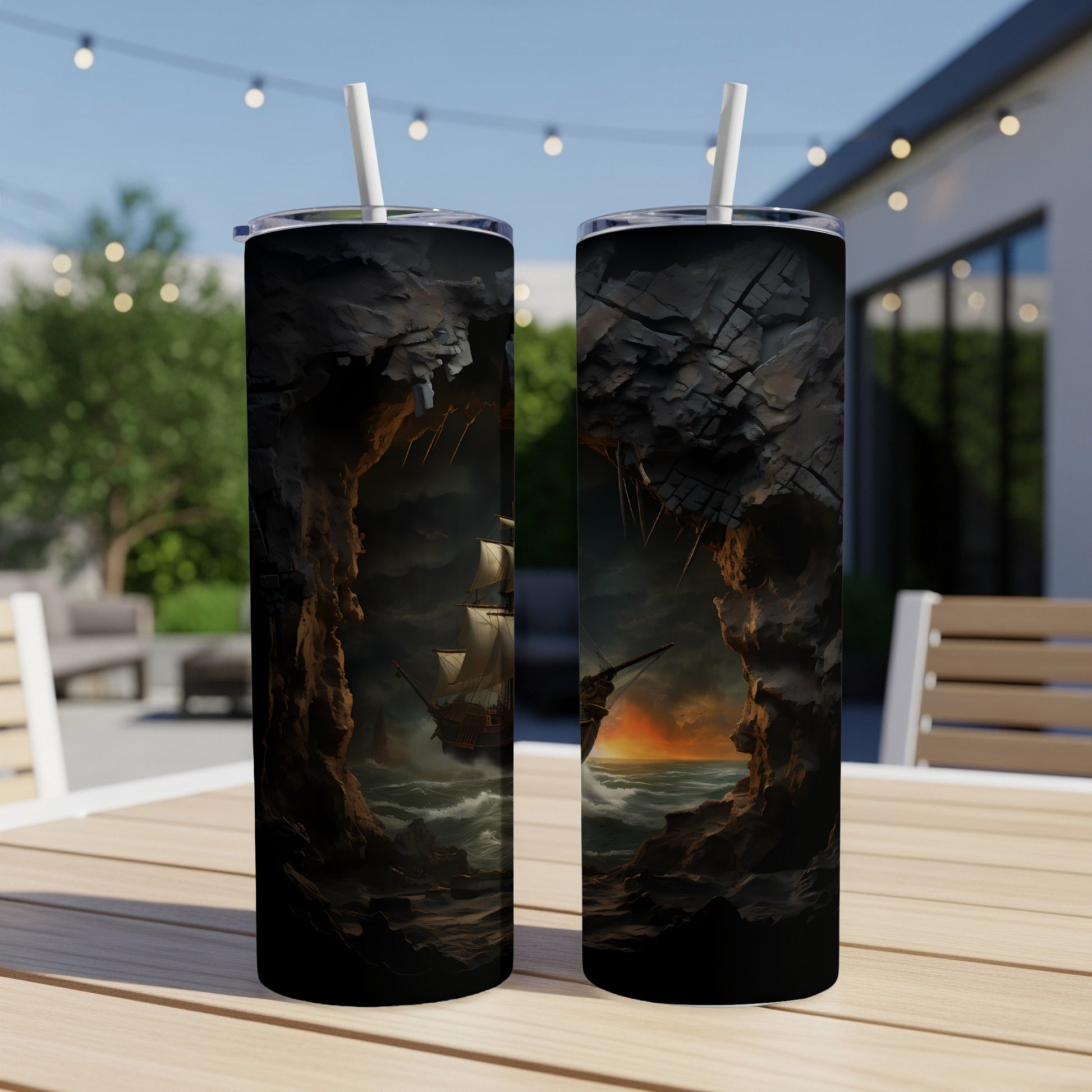 Two tumblers with a pirate ship emerging from a cave at sunset.
