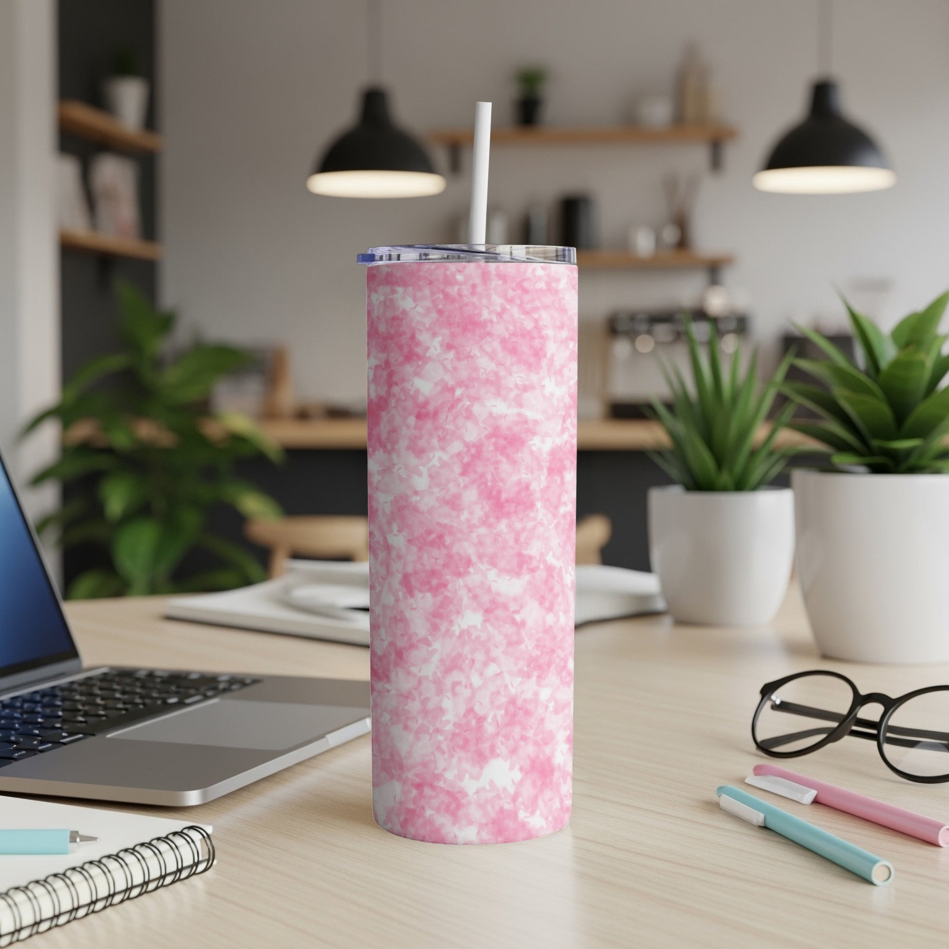 Pink marble pattern tumbler with straw on desk with laptop.