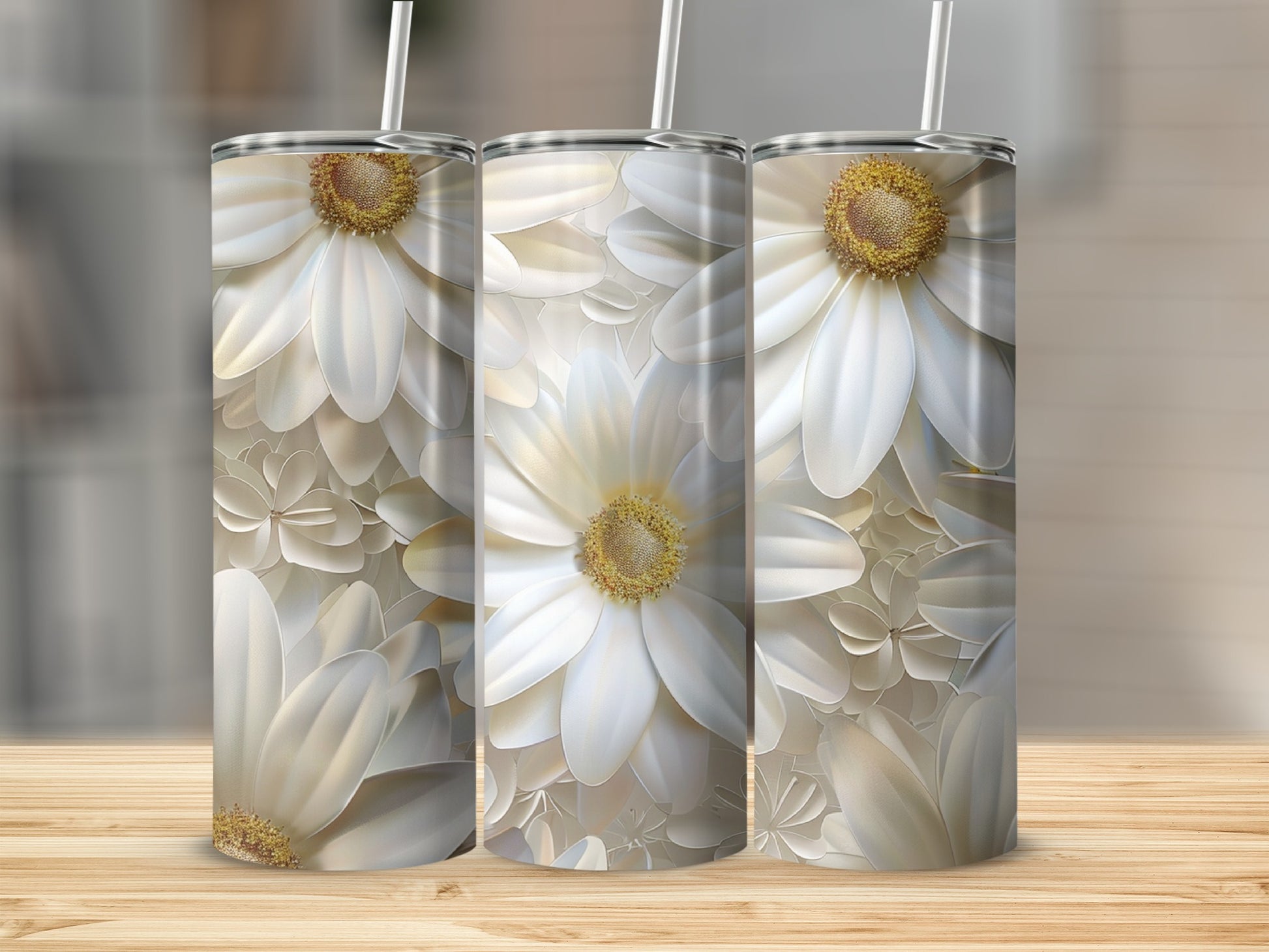 Three white floral tumblers with straws on a wooden surface.