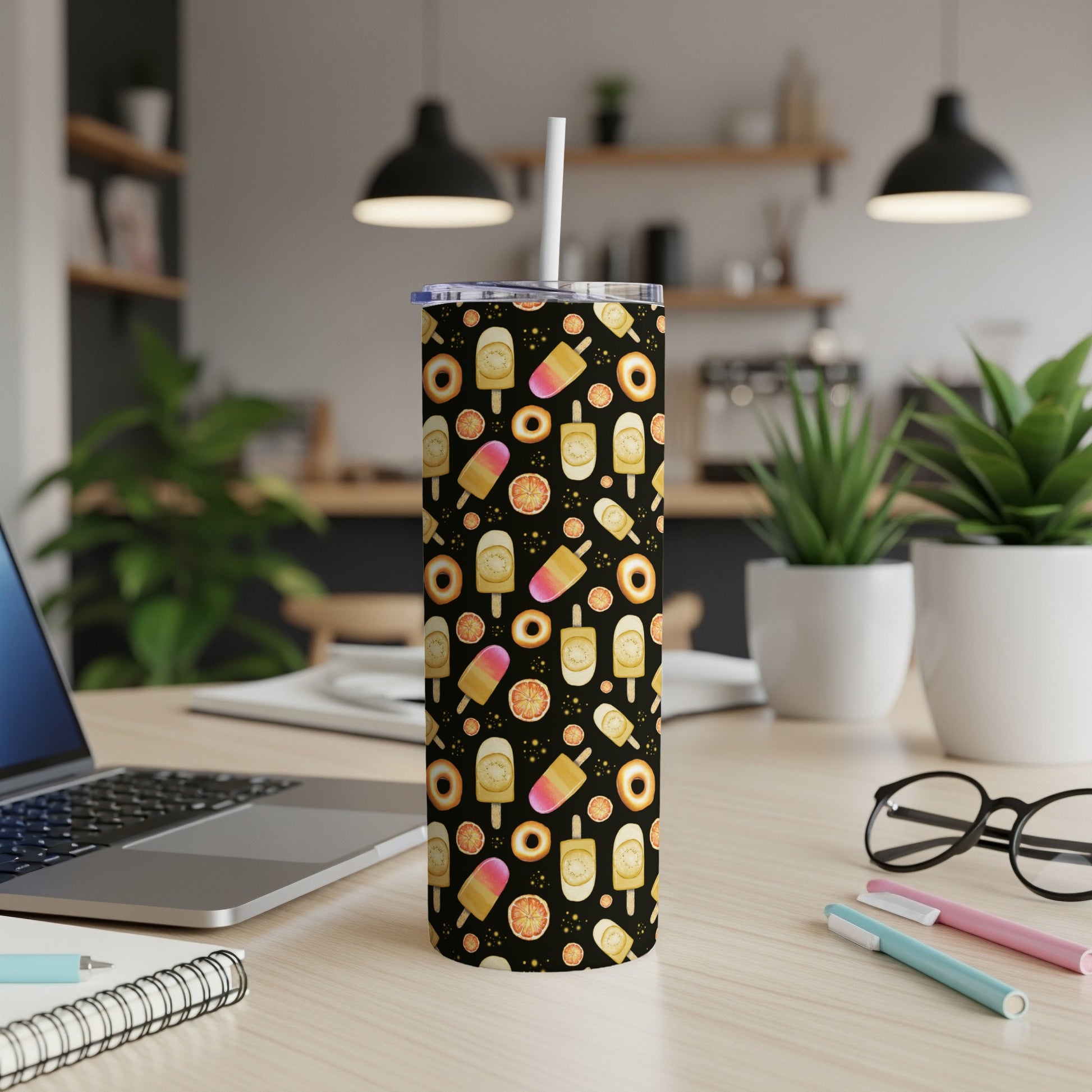 Black tumbler with colorful ice pops, donuts, and orange slice pattern, white straw.