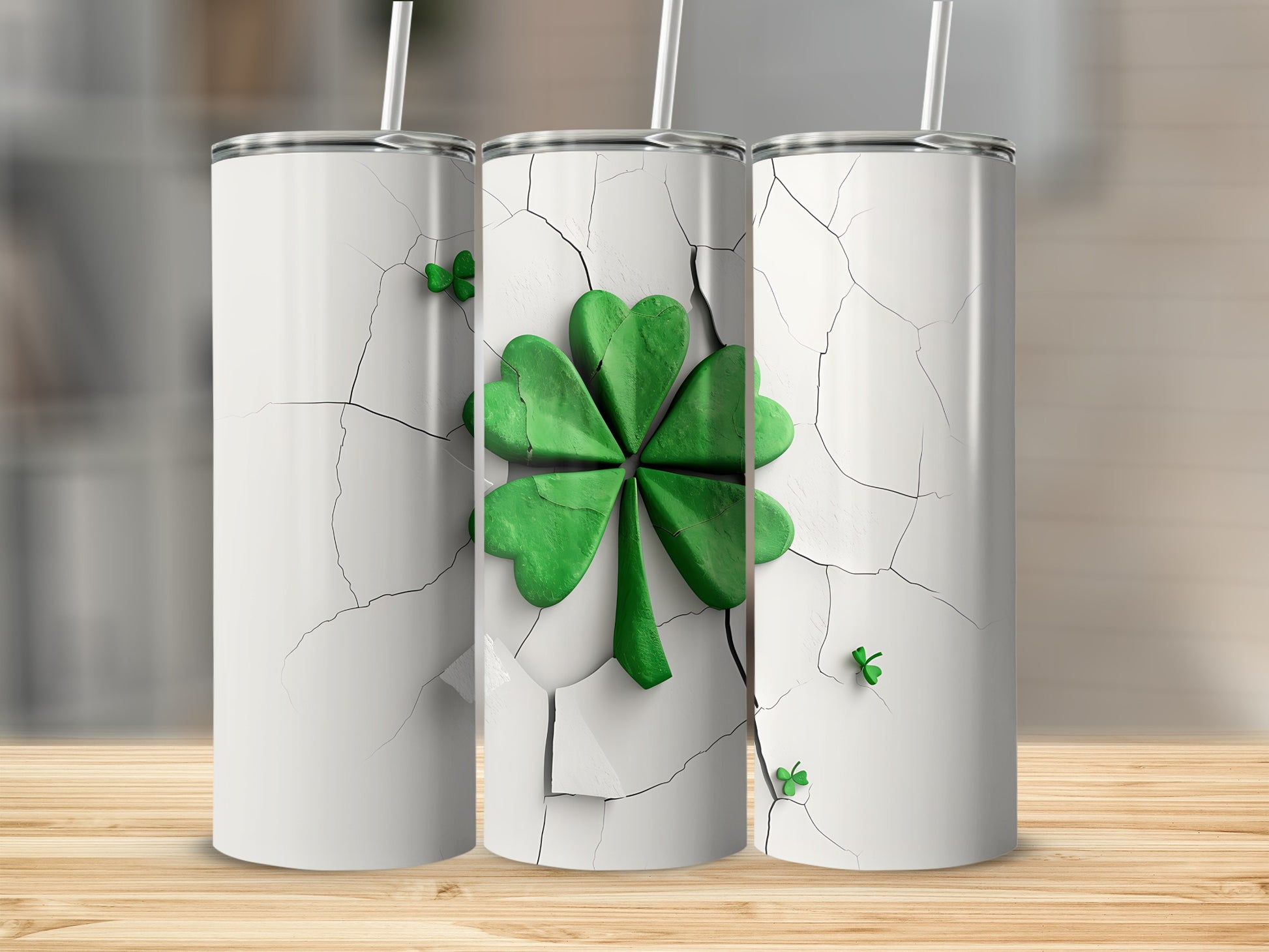 Three white tumblers with a green shamrock design on a wooden surface.