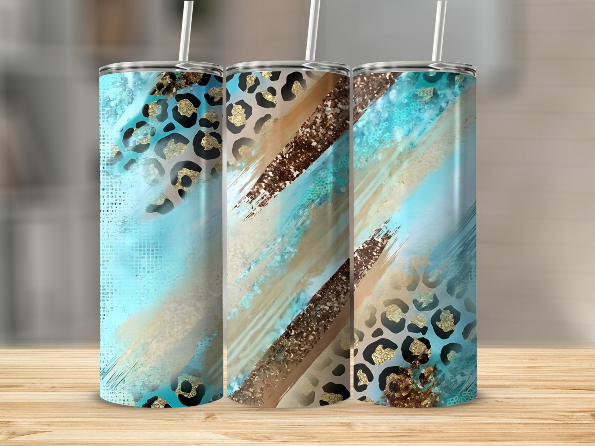 Three tumblers with teal, gold, and leopard print designs on a wooden surface.