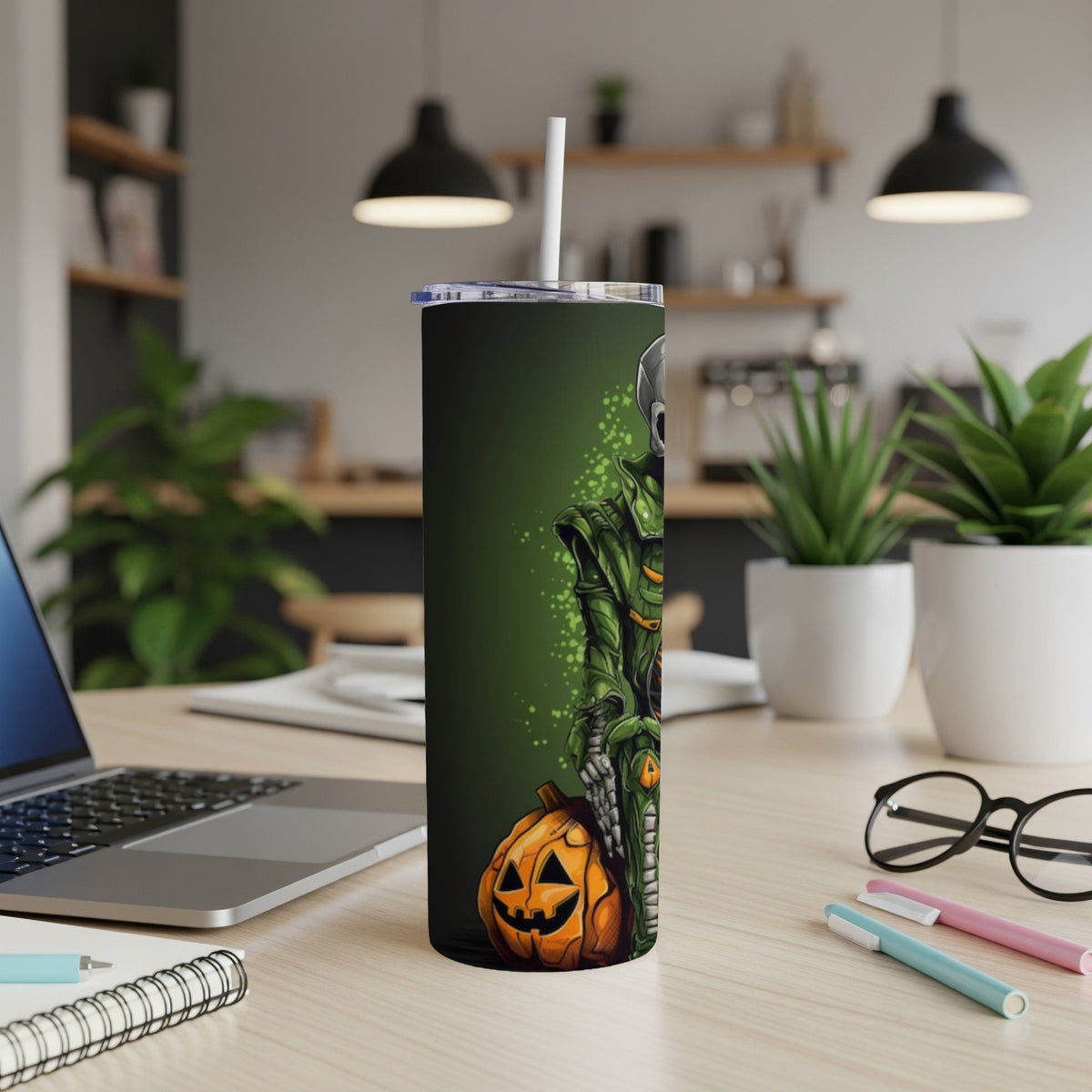 Tumbler with skeleton and pumpkin Halloween design on a desk.