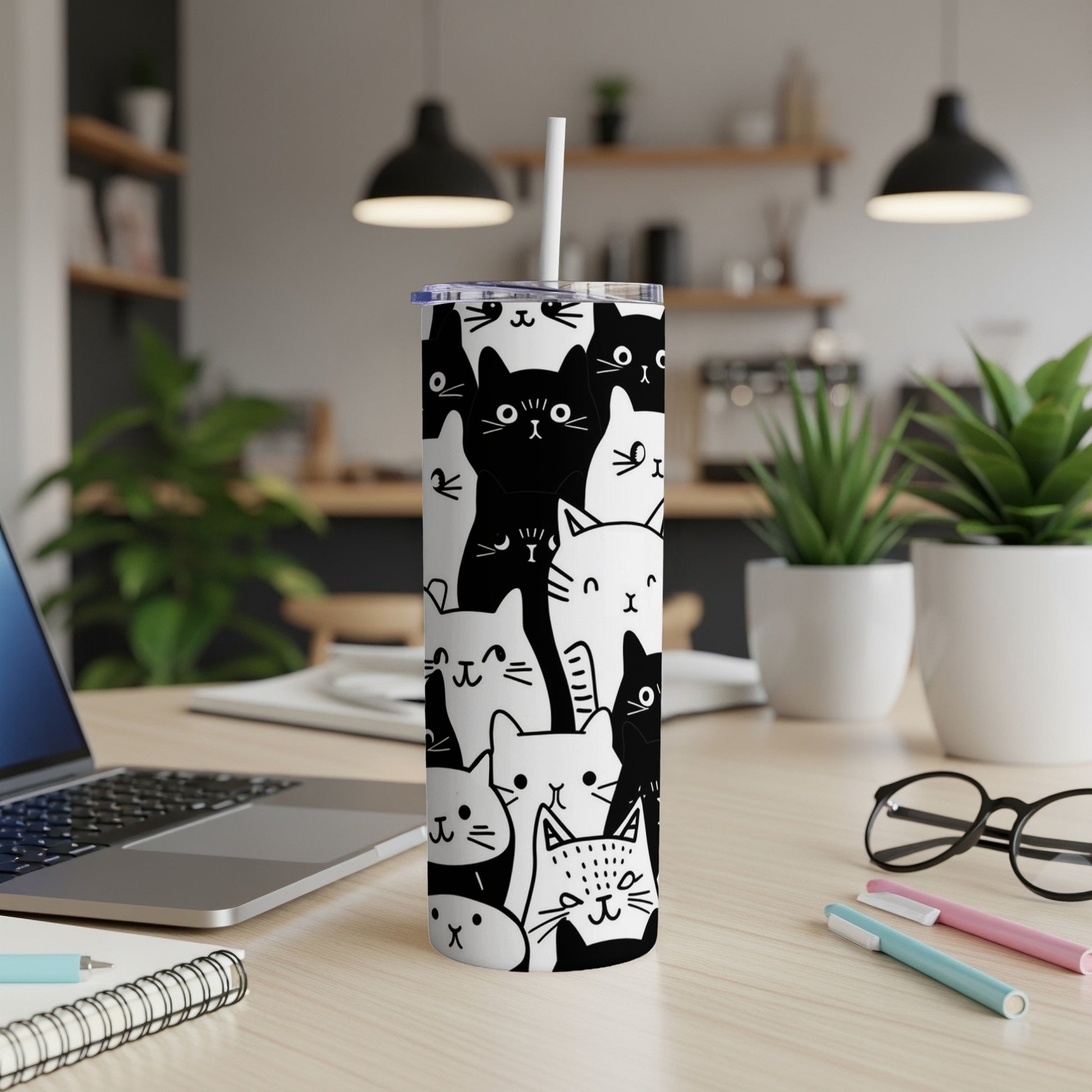 White tumbler with black and white cat illustrations, straw inserted.