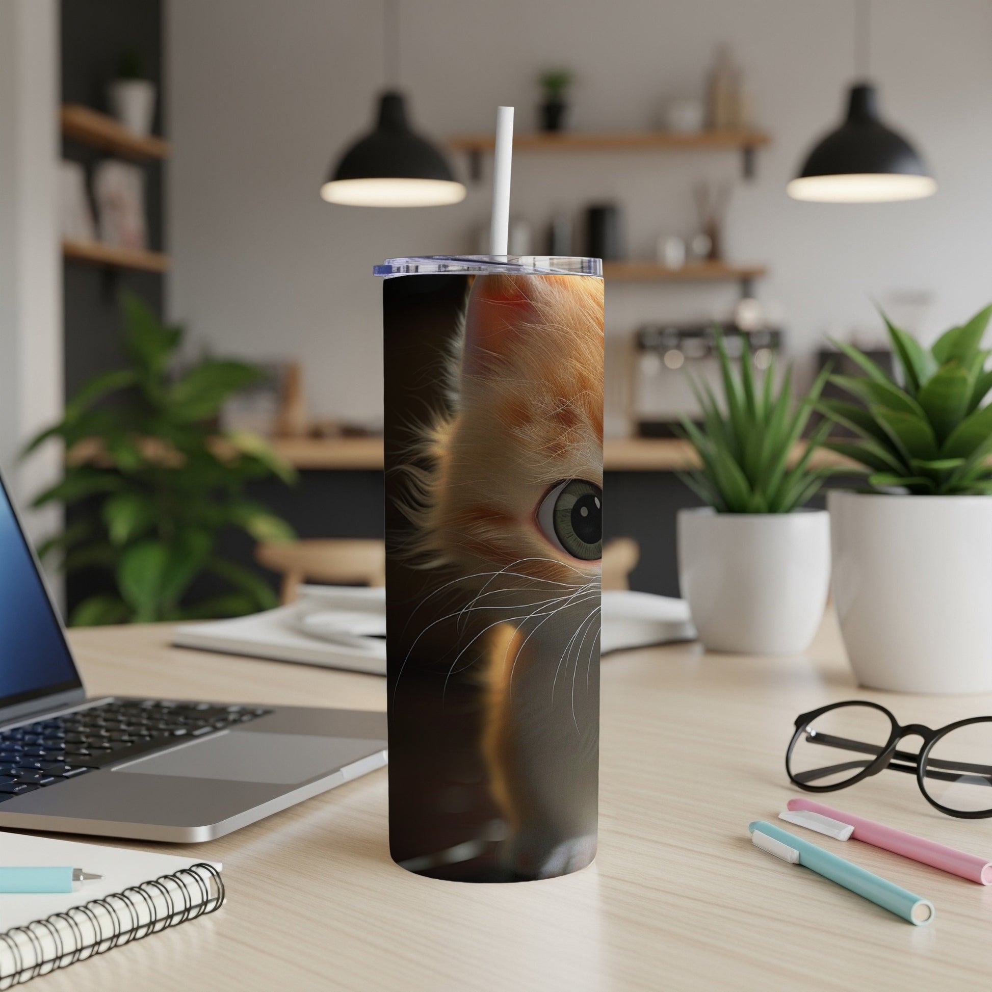 Orange tabby cat's eye on a tumbler with a straw, on a desk.