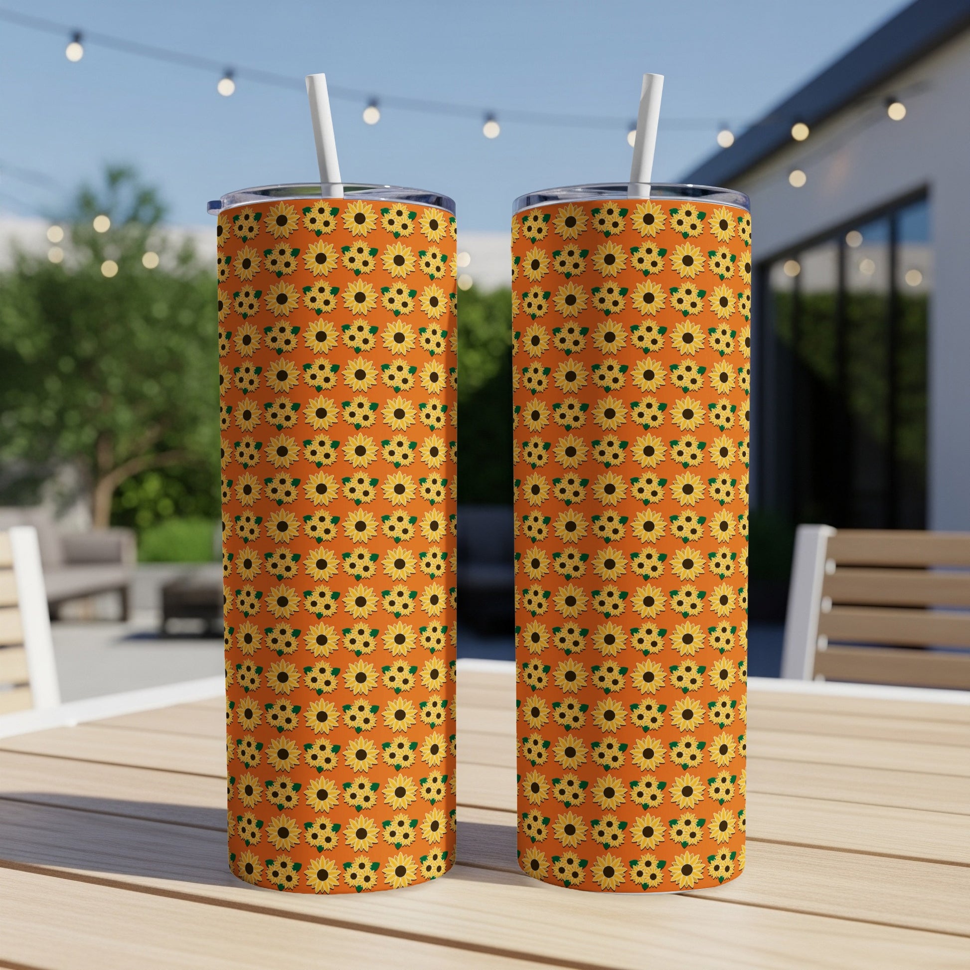 Two tall tumblers with sunflower pattern on an outdoor table.