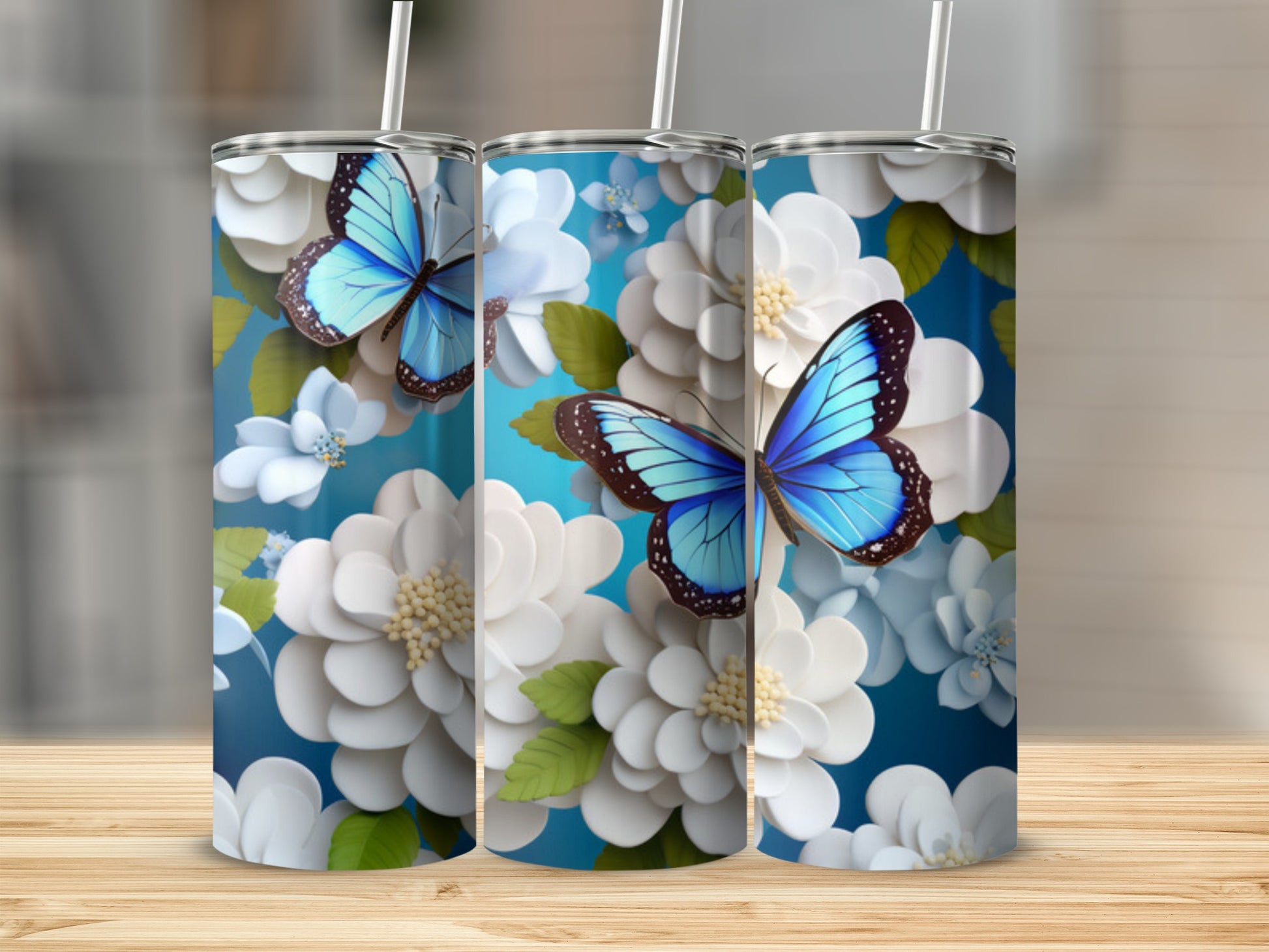 Three tumblers with blue butterflies and white flowers on a blue background.