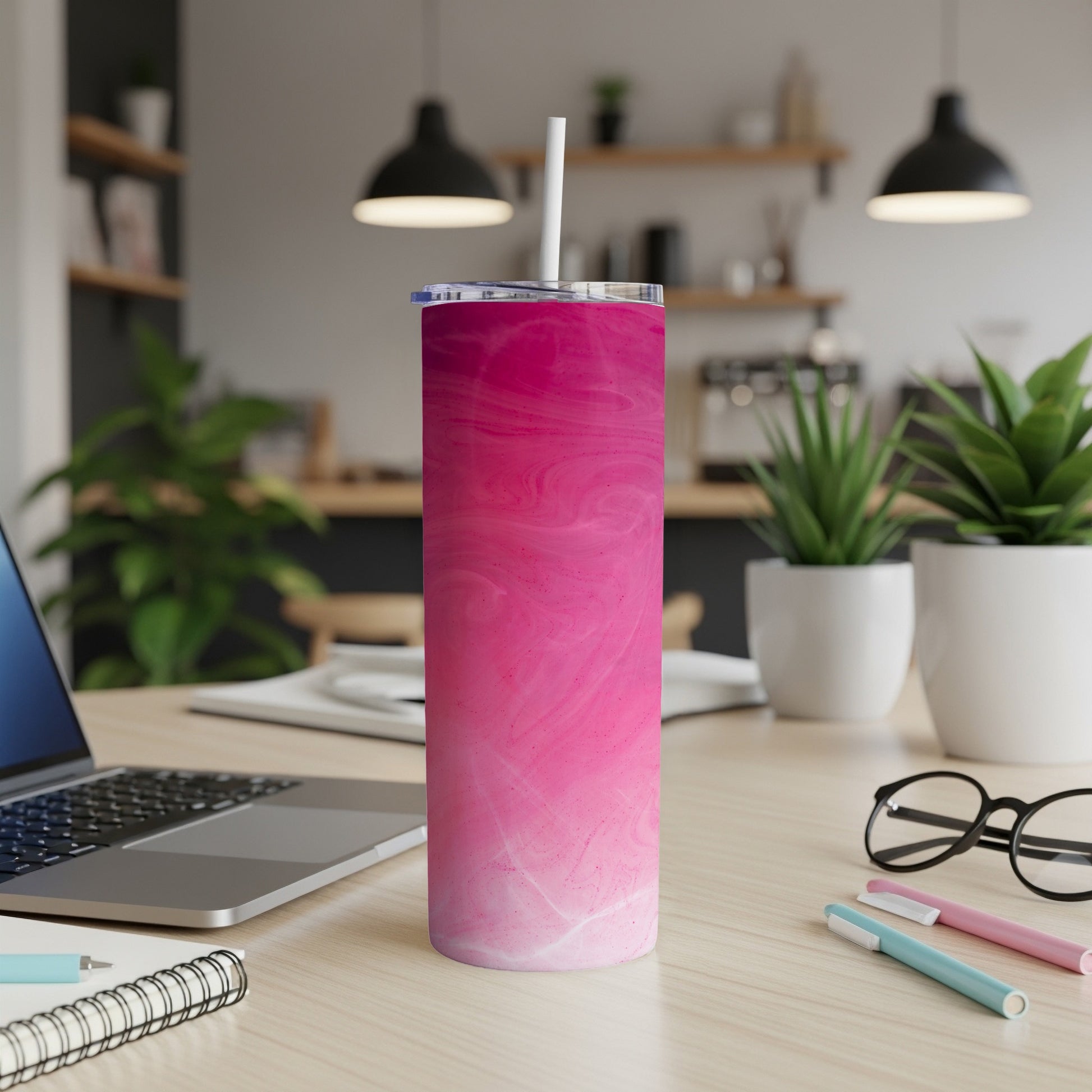 Pink and white marbled tumbler with straw on a desk.