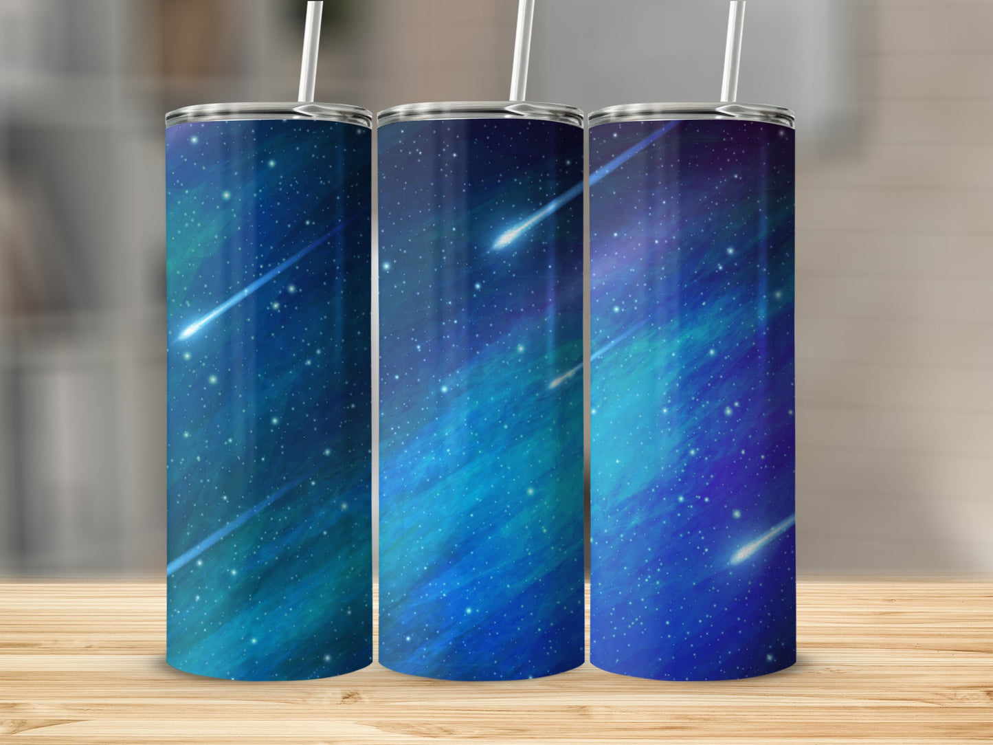 Three tumblers with a starry, blue and turquoise cosmic design and shooting stars.