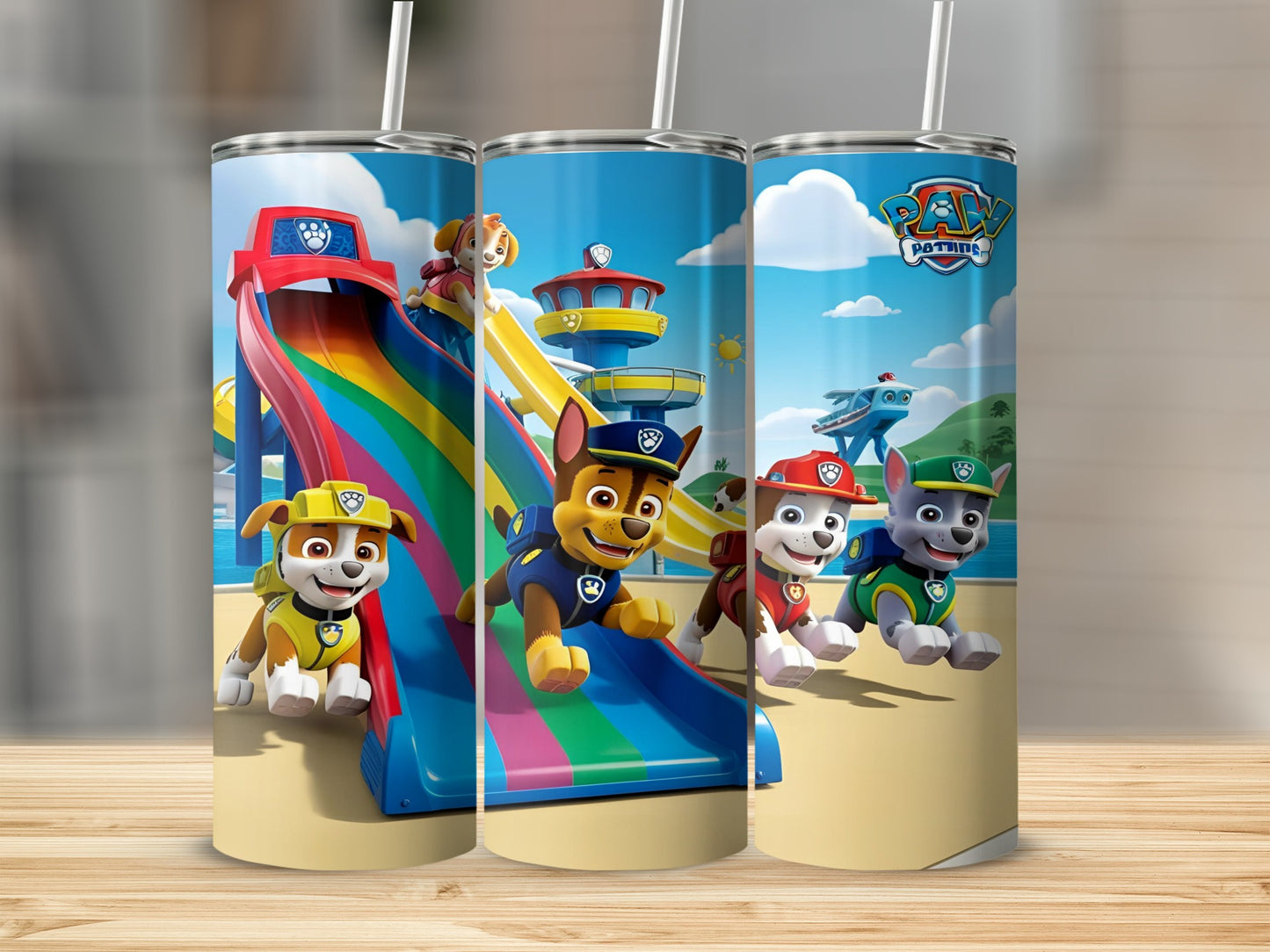 Paw Patrol characters slide down a rainbow on a beach under a blue sky.