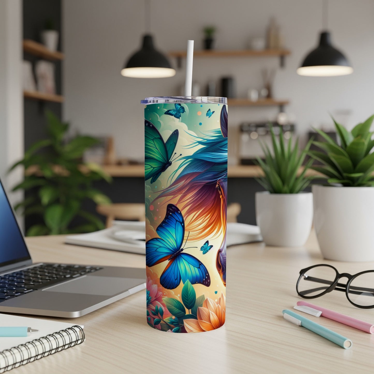 Blue butterfly design on a tall, white tumbler with a straw, on a desk.