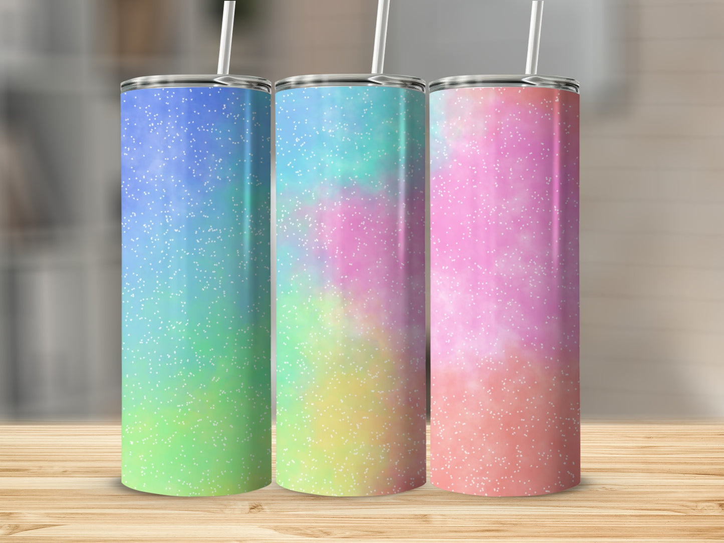 Three tumblers with glittery, ombre pastel designs and white straws.
