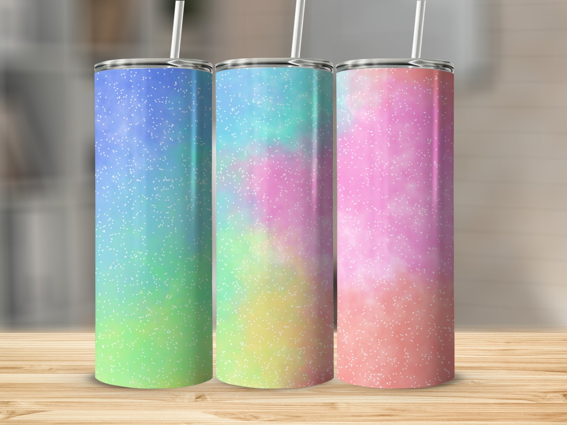 Three tumblers with glittery, ombre pastel designs and white straws.