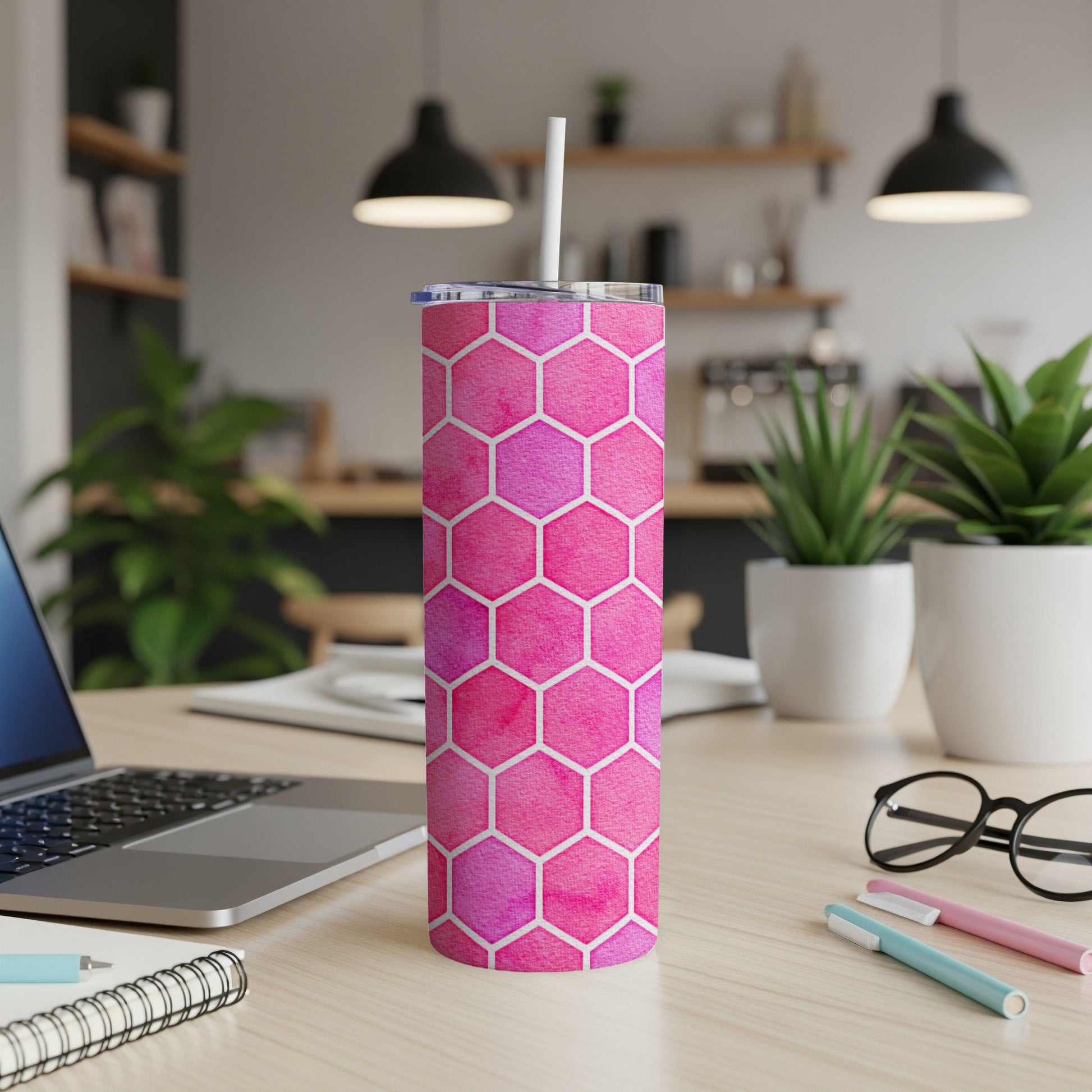 Pink hexagon pattern tumbler with a white straw on a desk.