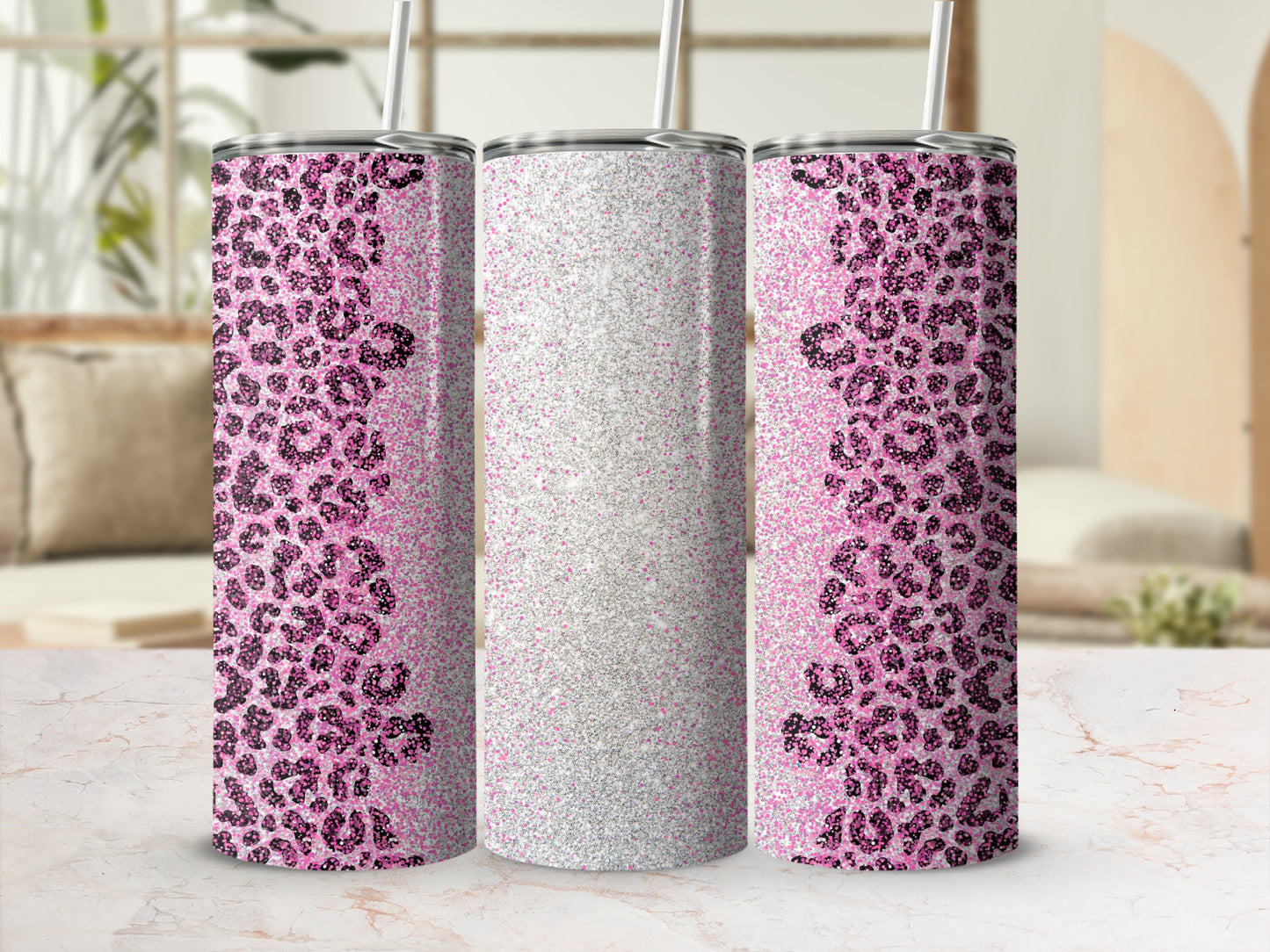 Pink leopard print and glitter tumbler with straw on marble surface.