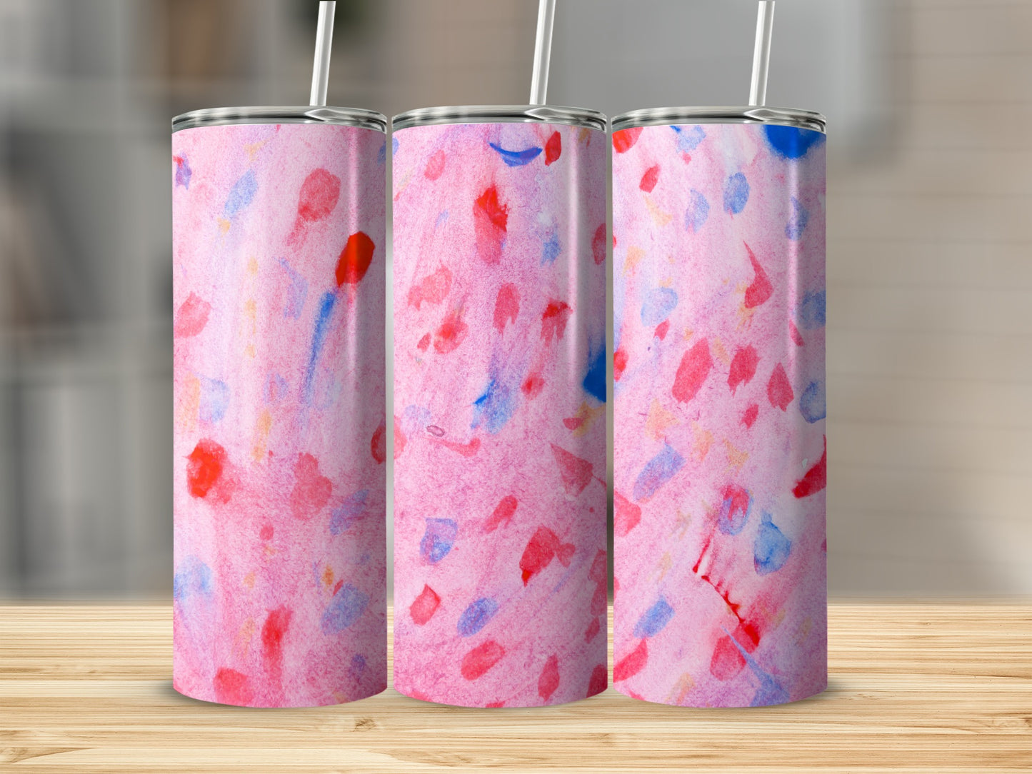 Three pink tumblers with watercolor splatters of red and blue.