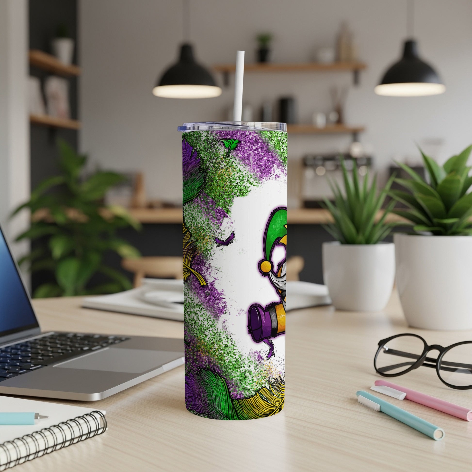 Mardi Gras tumbler with jester and feathers on desk.
