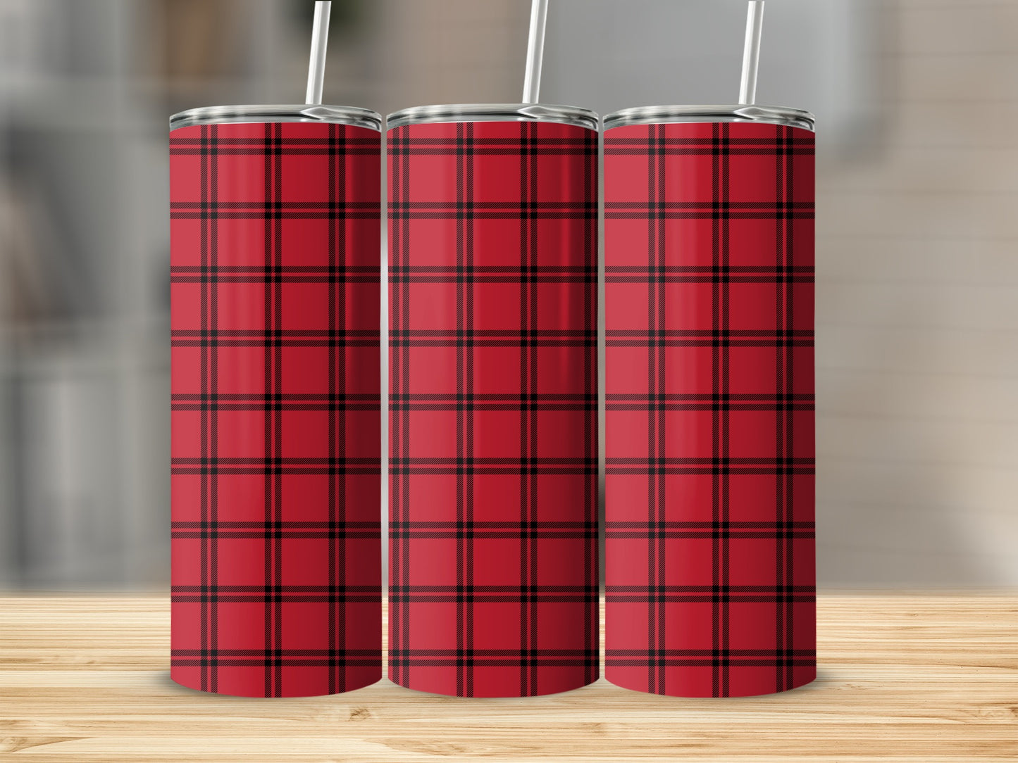 Three red plaid tumblers with straws on a wooden surface.