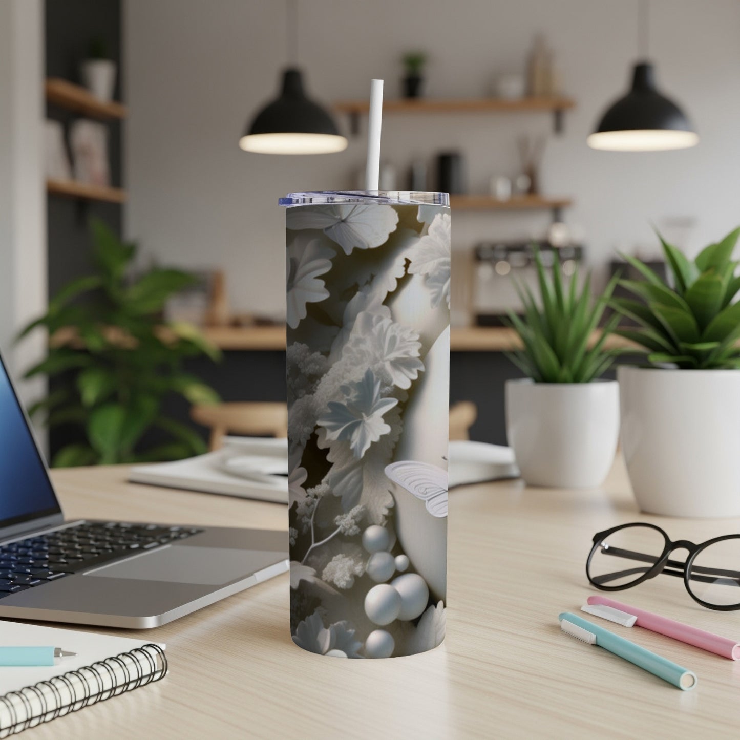 White tumbler with floral and butterfly pattern on a desk.