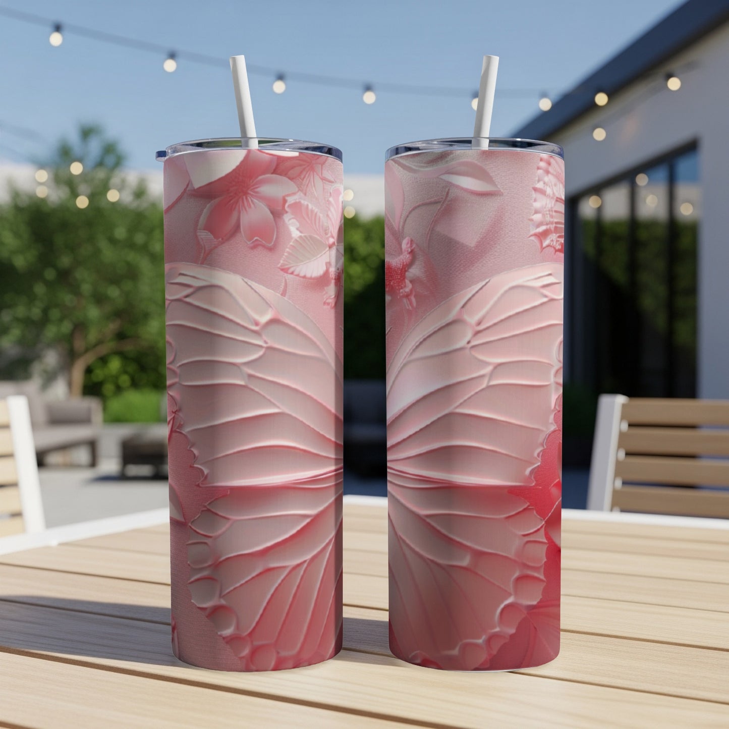 Two pink butterfly wing patterned tumblers with straws on a table.