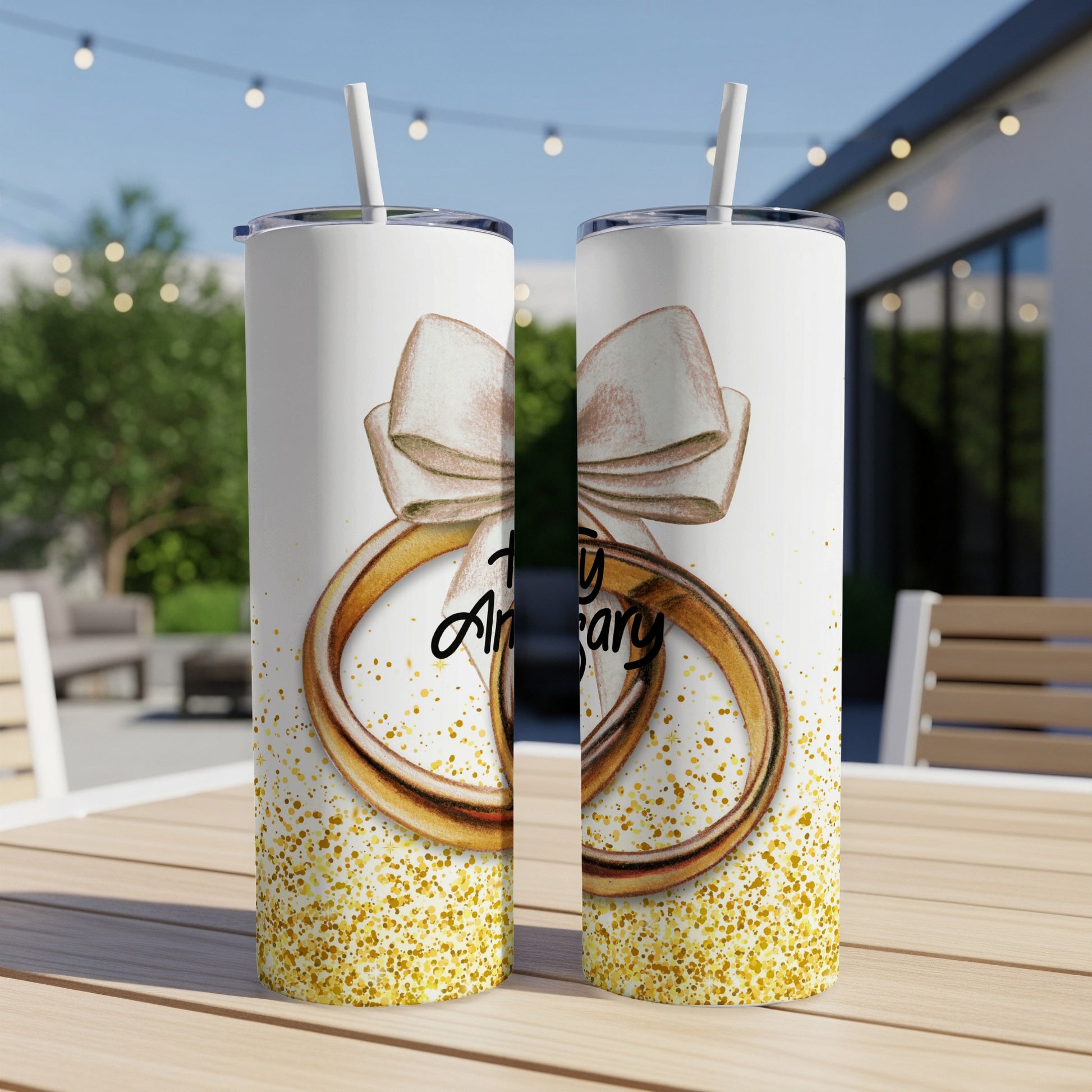 Two tumblers with wedding rings, bow, and "Anniversary" text, on a table.