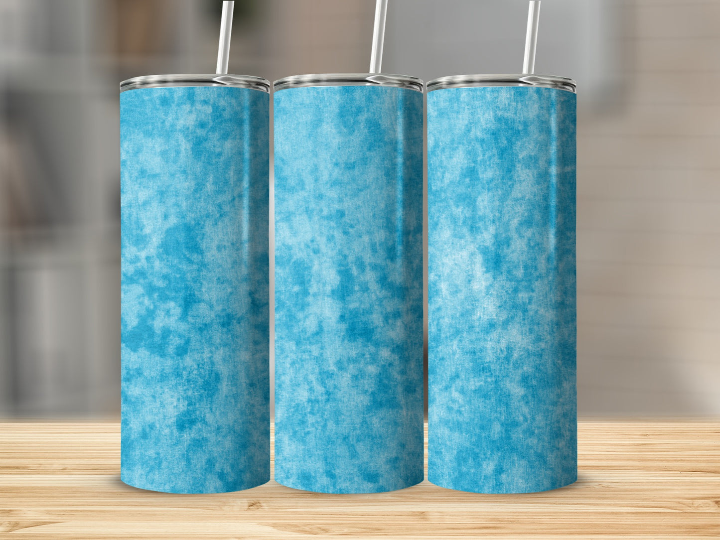 Three blue textured tumblers with straws stand on a wooden surface.