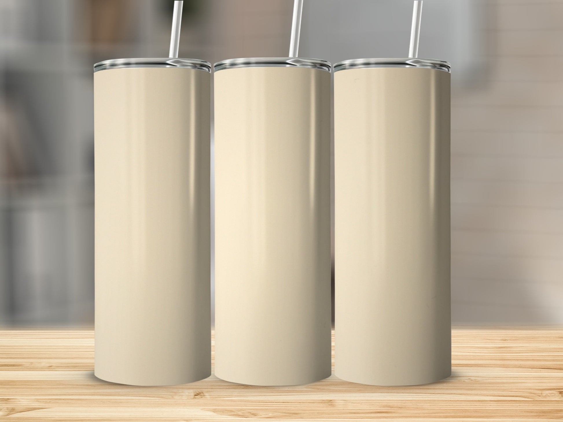 Three plain beige tumblers with straws stand on a wooden surface.