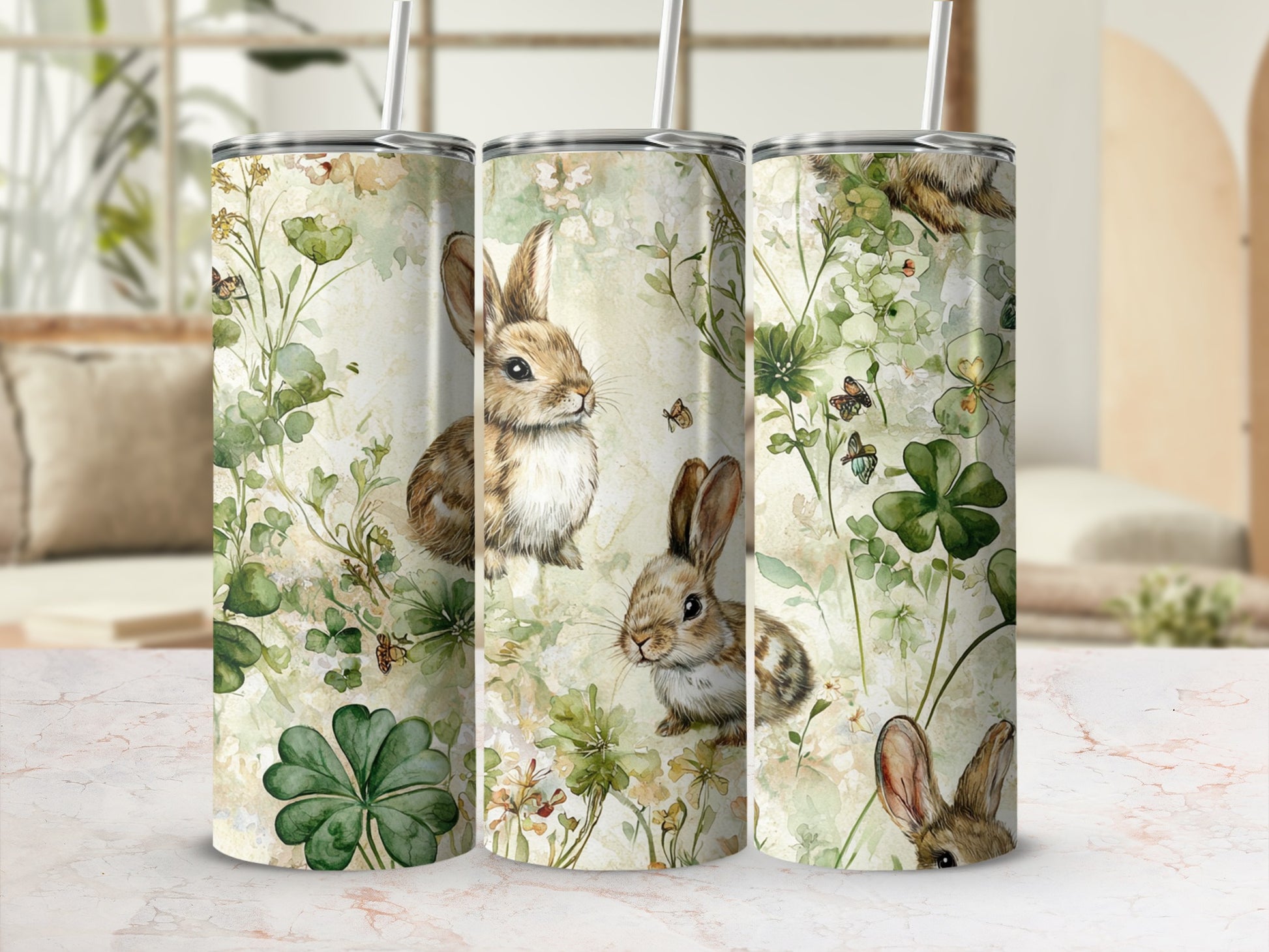 Three tumblers with bunny and floral illustration, set on a marble counter.