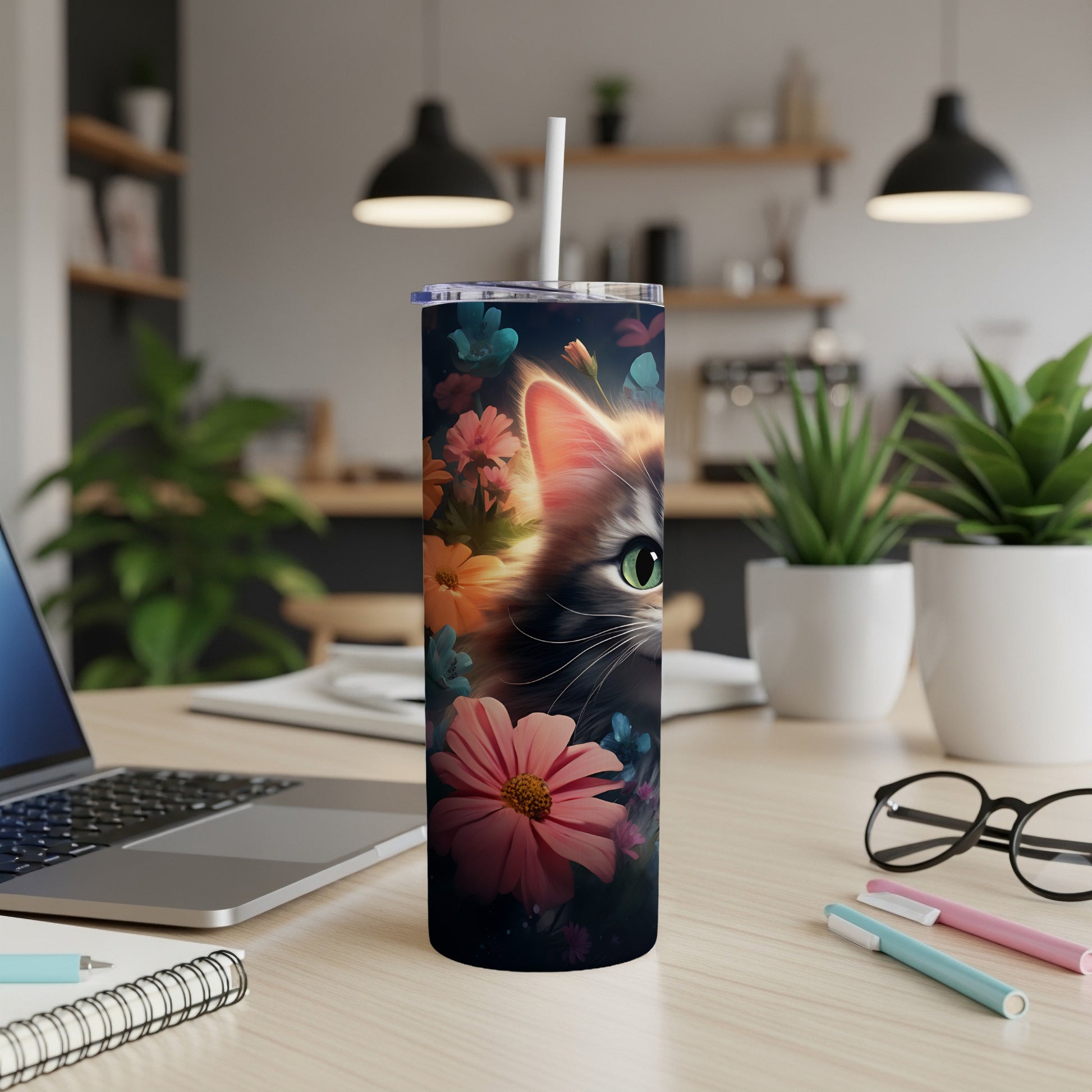 Cat's eye peeking through floral design on a skinny tumbler with straw.