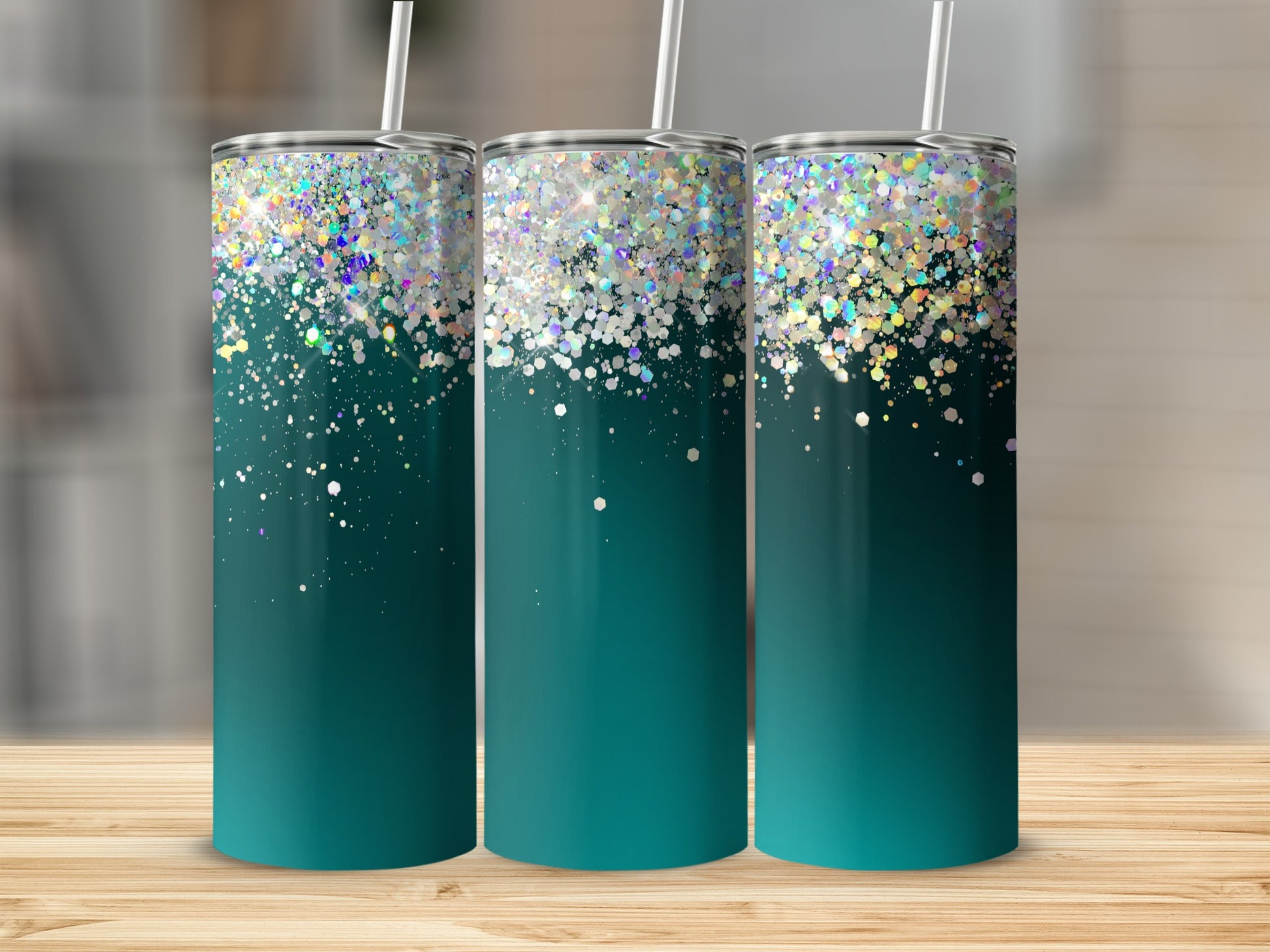 Three teal tumblers with glitter design and straws on a wooden surface.
