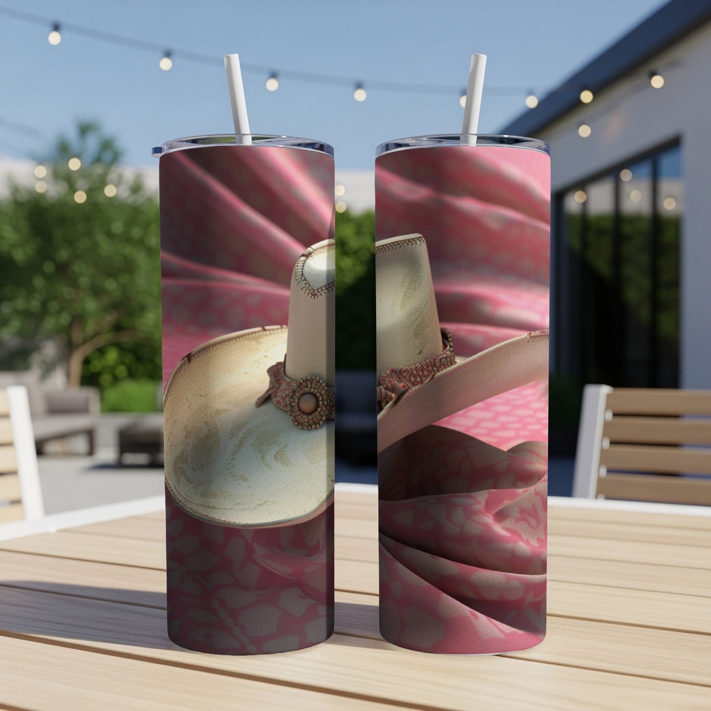 Two tumblers with cowboy hats and pink patterned fabric on a wooden table.