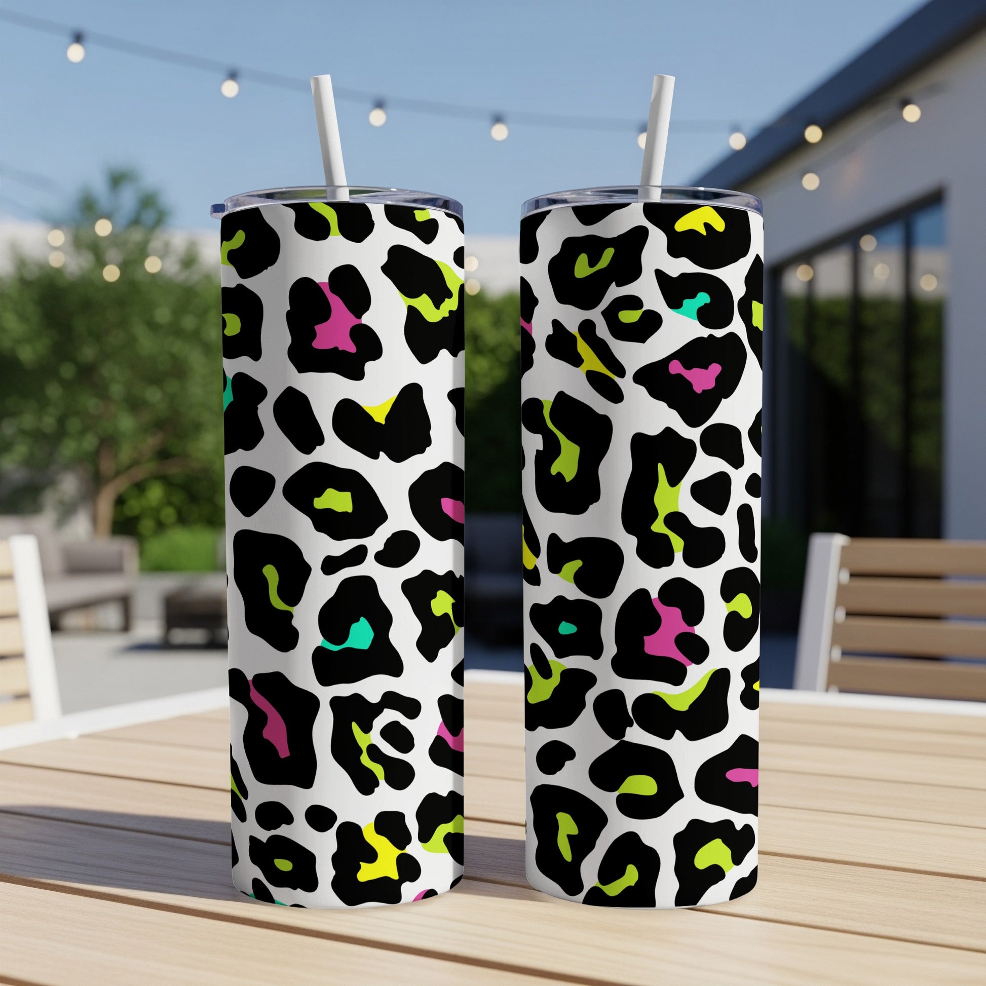 Two tumblers with a colorful leopard print pattern sit on a wooden table.