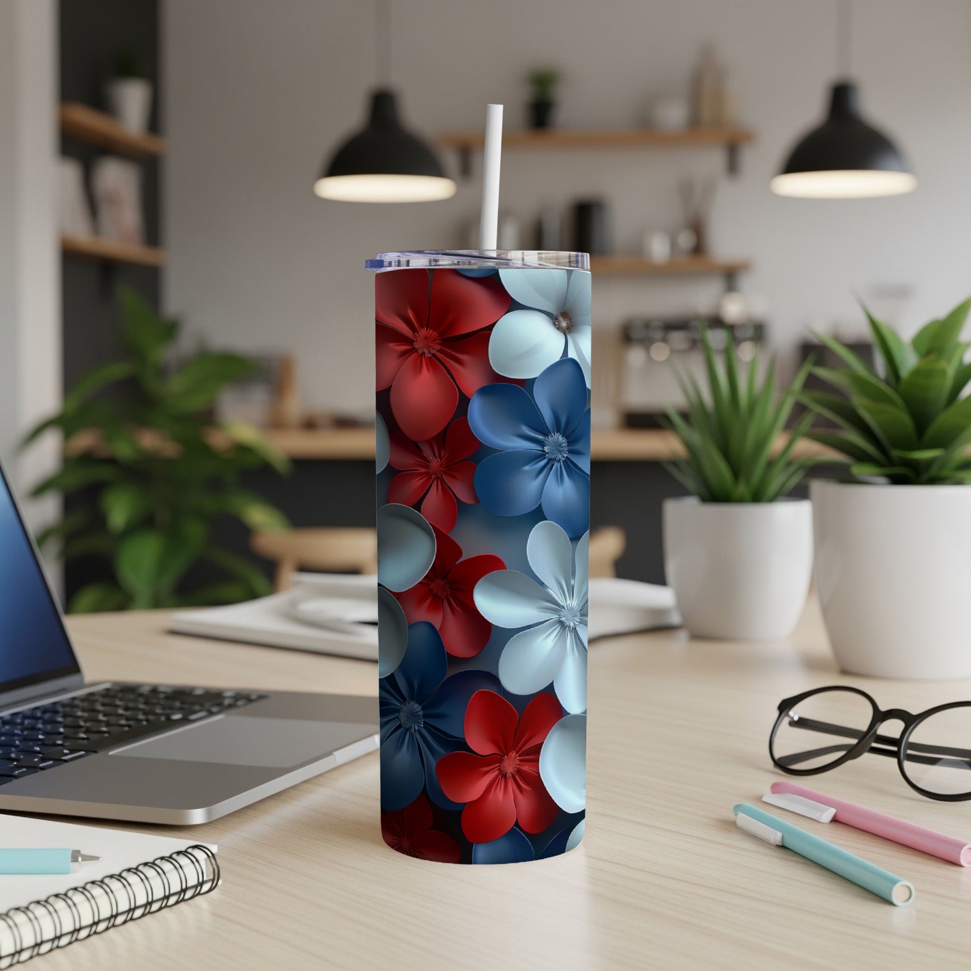 Red, white, and blue floral tumbler with straw on a desk.