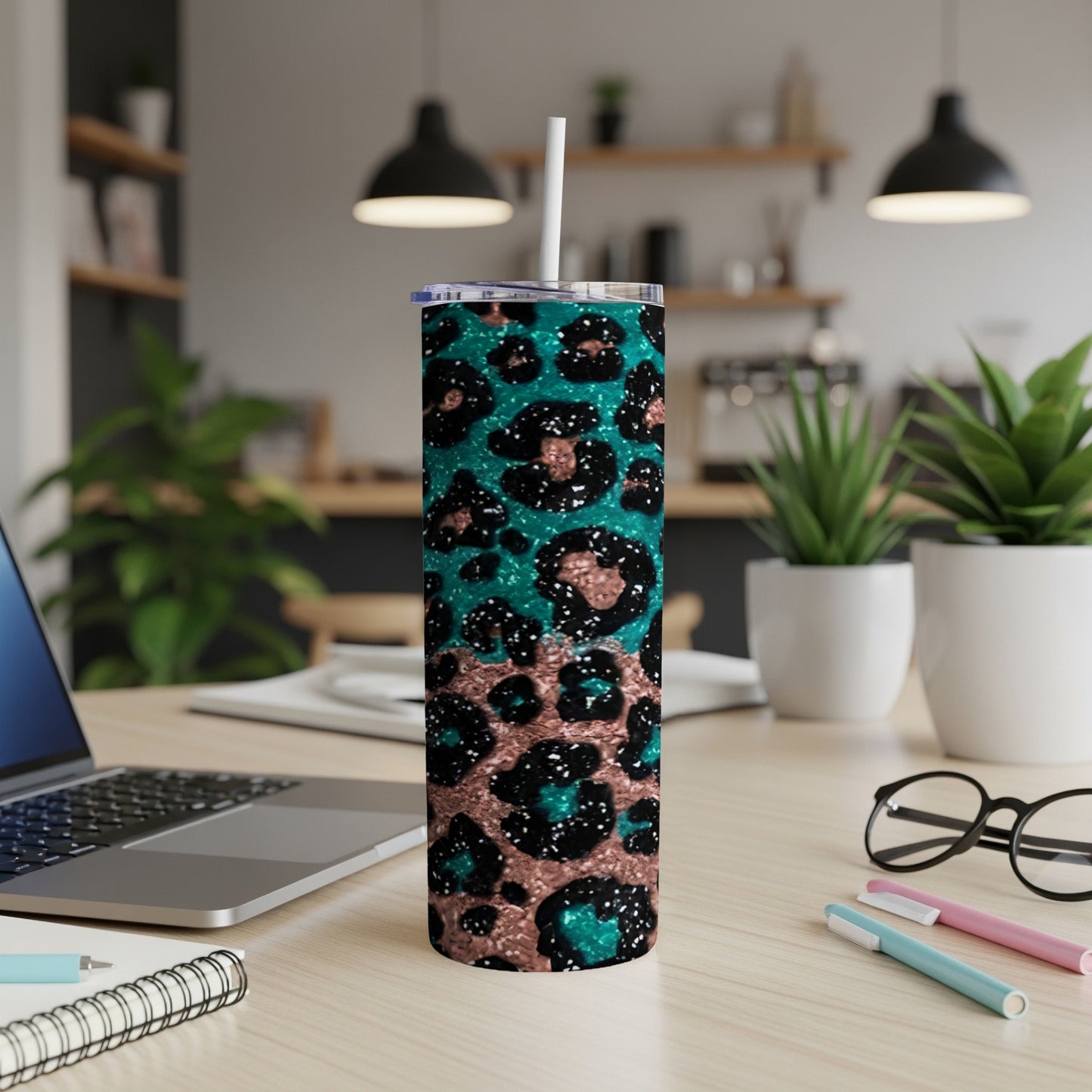 Teal and rose gold glitter leopard print tumbler with straw on desk.
