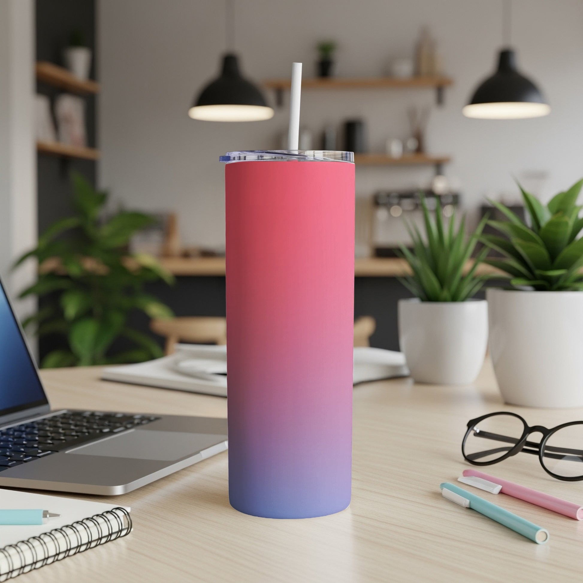 Gradient pink to blue insulated tumbler with straw on a desk.