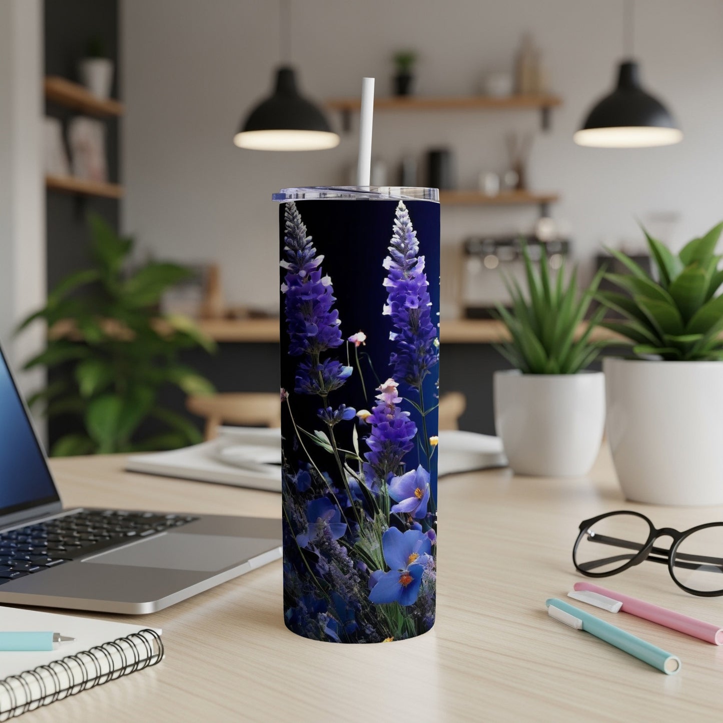 Tall tumbler with purple flowers and dark blue background on desk.