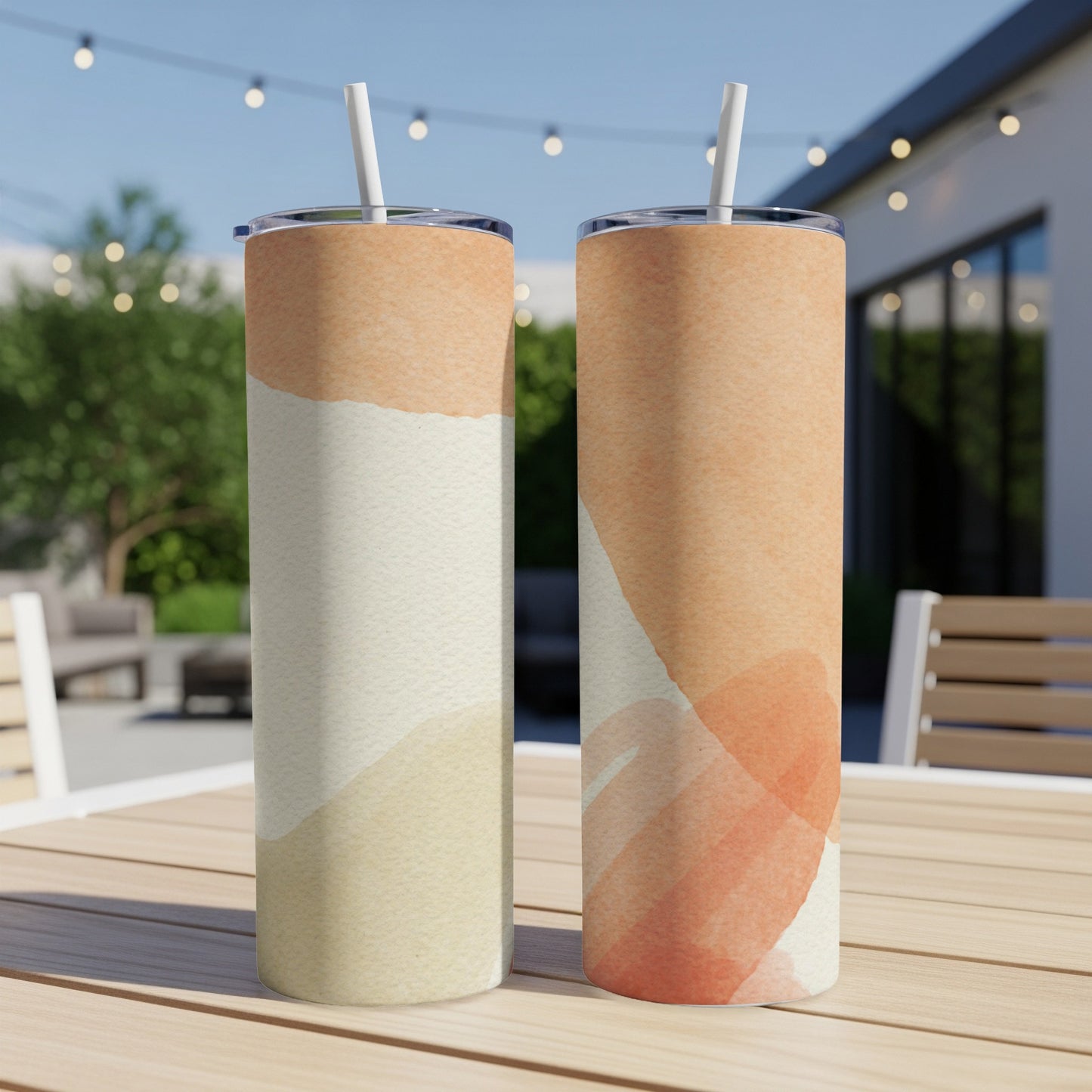 Two tumblers with abstract watercolor designs on an outdoor table.