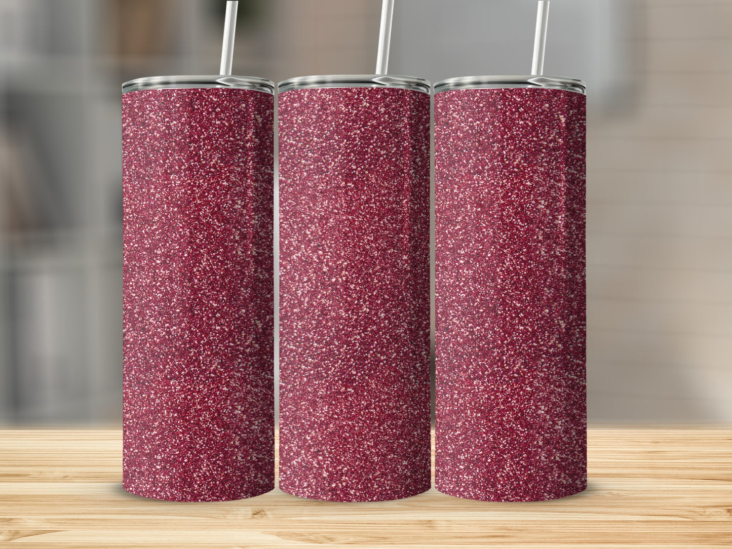 Three glitter tumblers with straws arranged in a line.