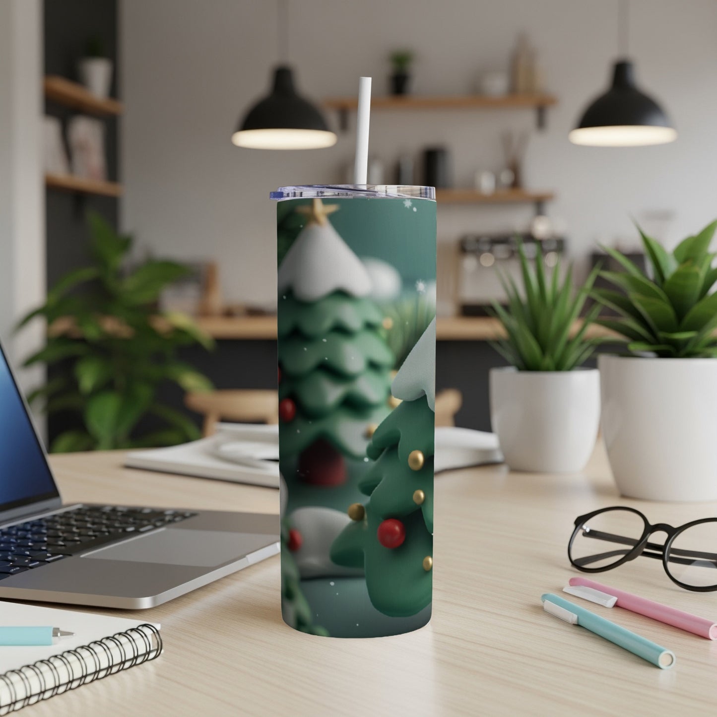 Festive Christmas tree tumbler with snow and red ornaments on a desk.