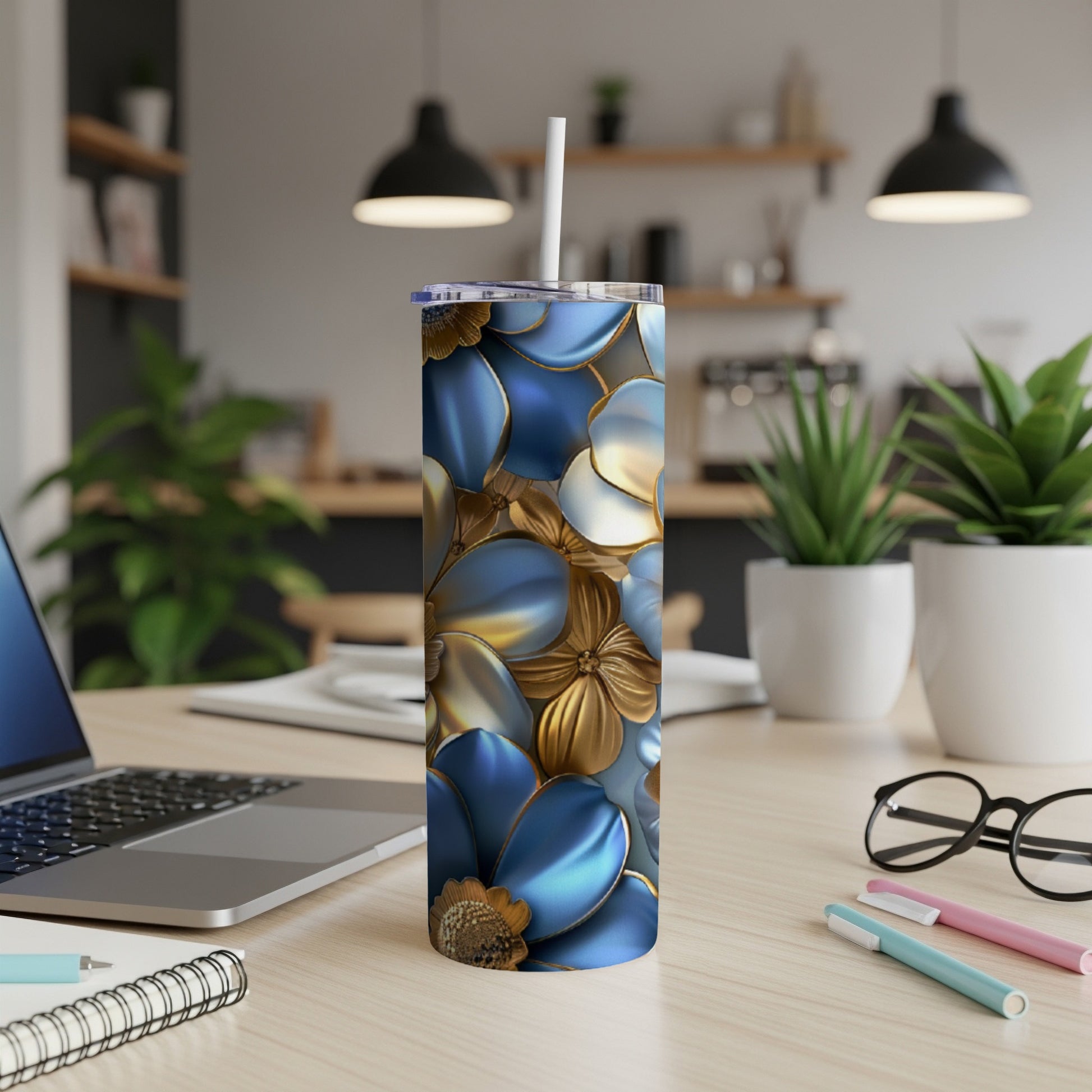 Blue and gold floral patterned tumbler with straw on a desk.