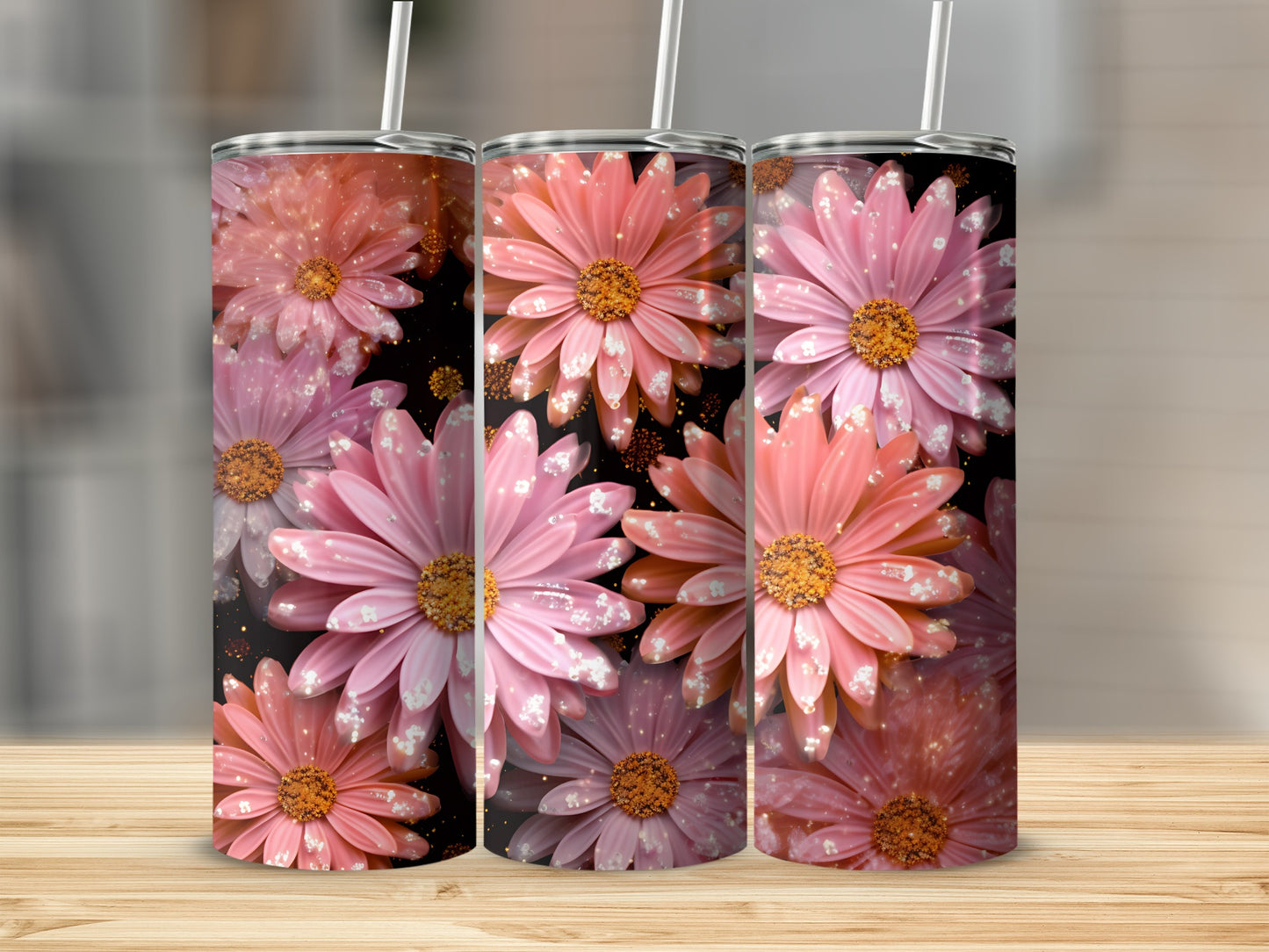 Three pink floral tumblers with glitter accents on a wooden surface.