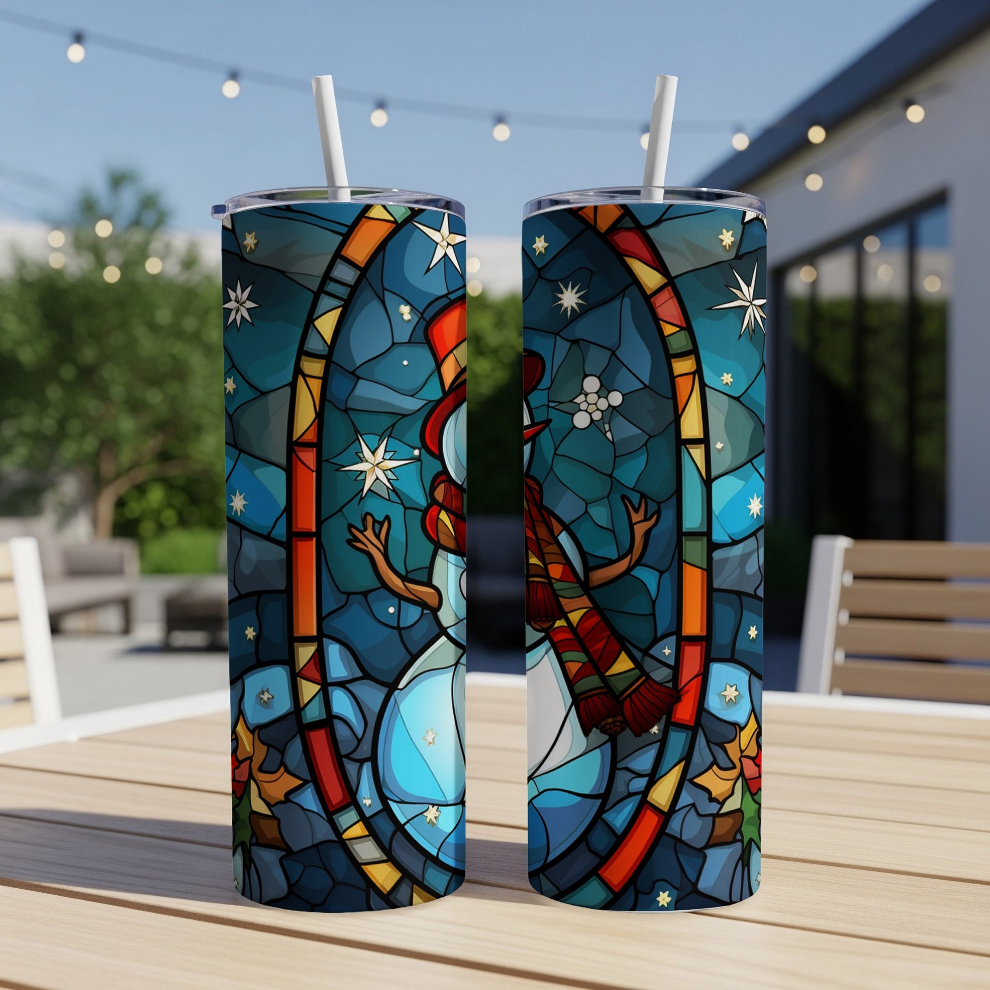 Stained glass snowman tumbler with straw on outdoor table.