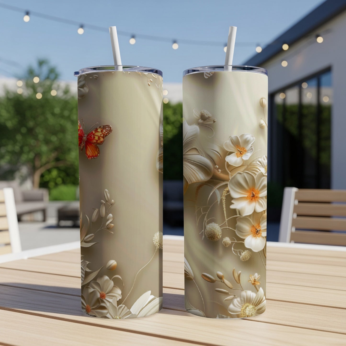 Two tall tumblers with a floral and butterfly design on a table.