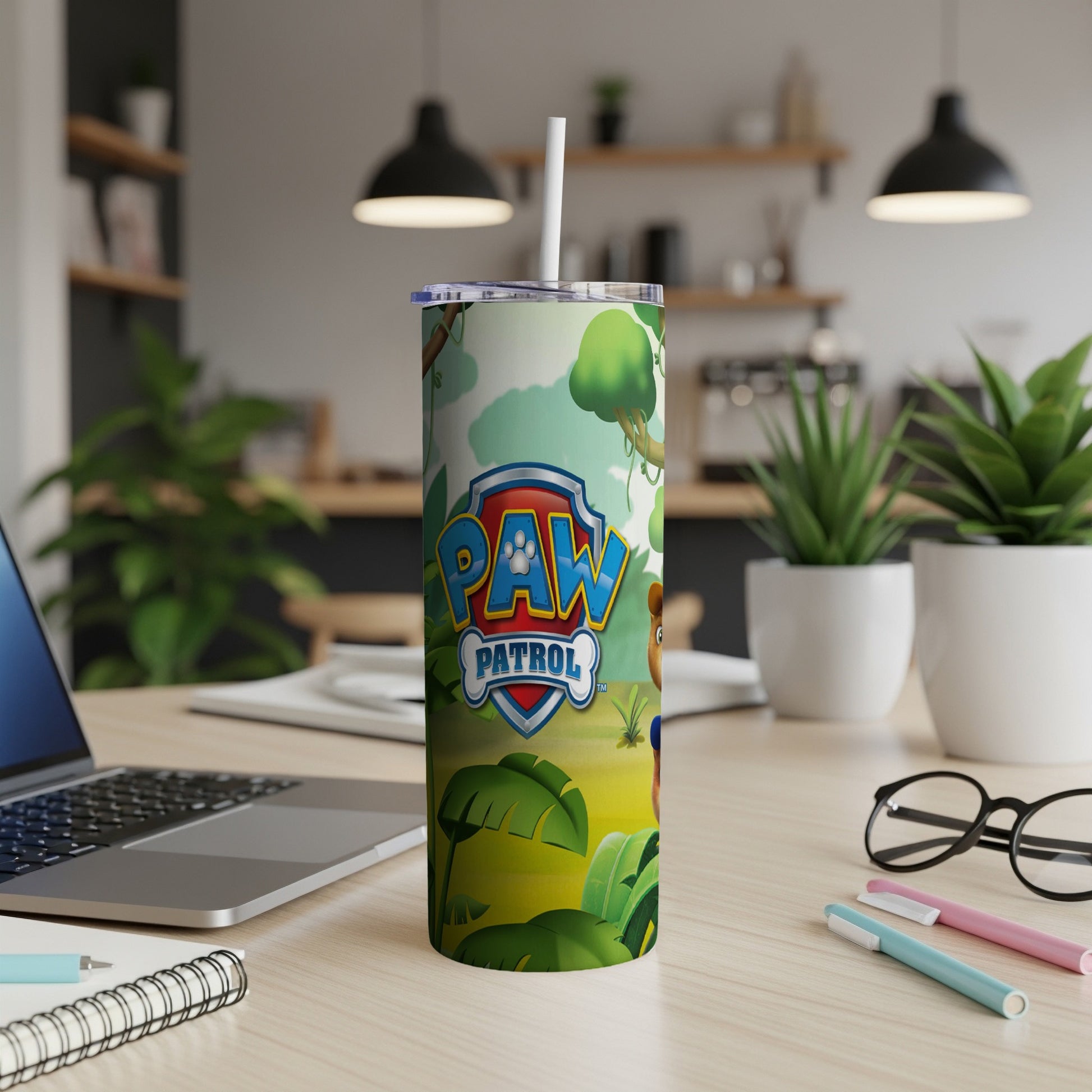 Paw Patrol tumbler with jungle scene and laptop on desk.