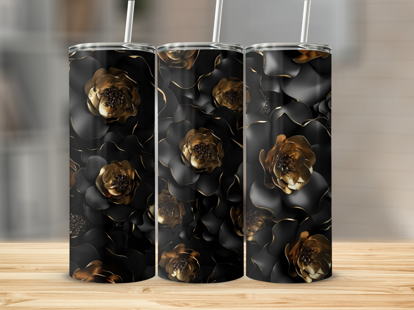 Three tumblers with black and gold floral design on a wooden surface.