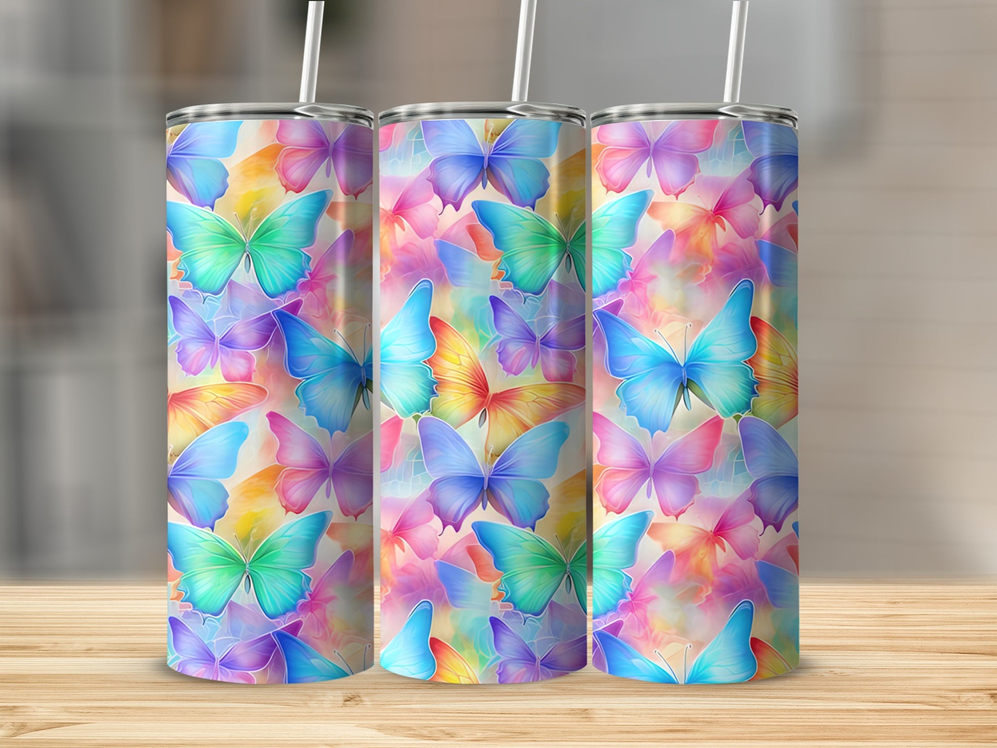 Three tumblers with colorful butterfly patterns on a wooden surface.