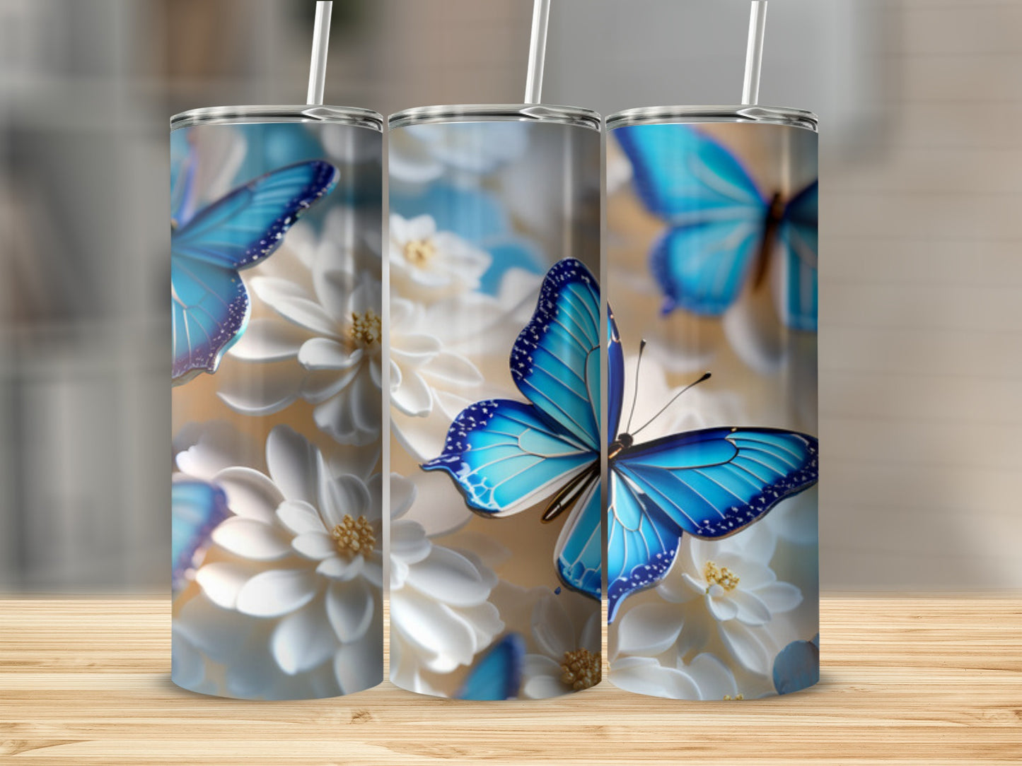 Three tumblers with blue butterflies and white flowers on a wooden surface.